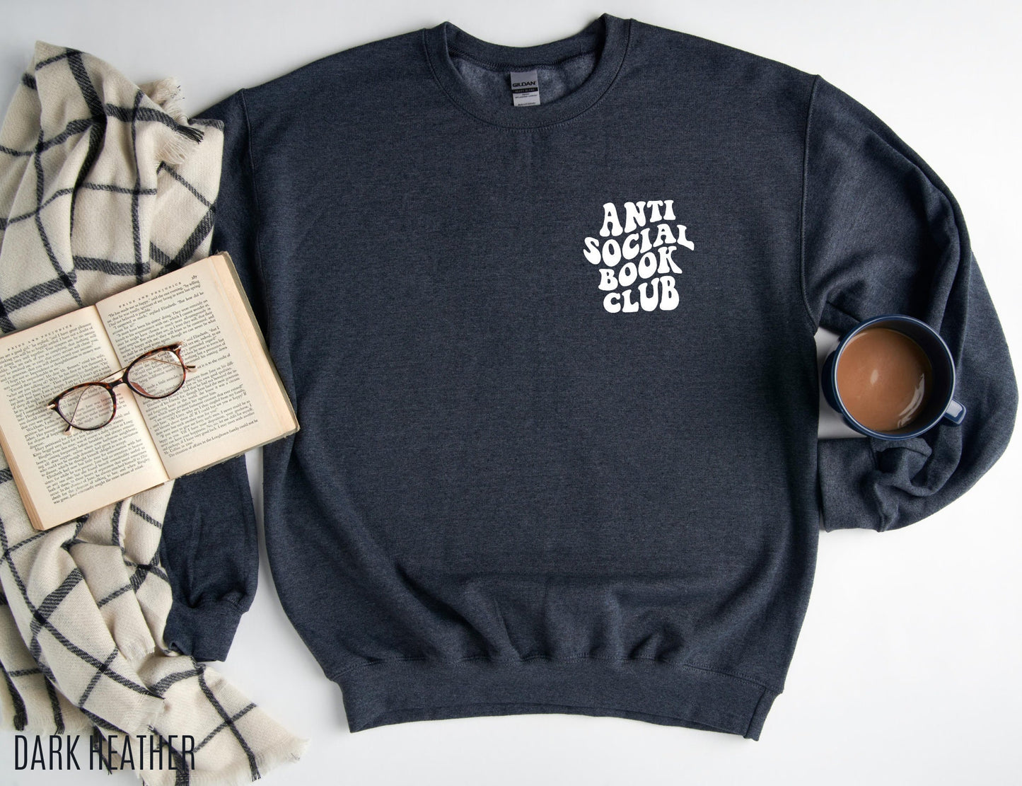 dark heather sweatshirt with anti social book club text laid flat with coffee, open book and plaid blanket