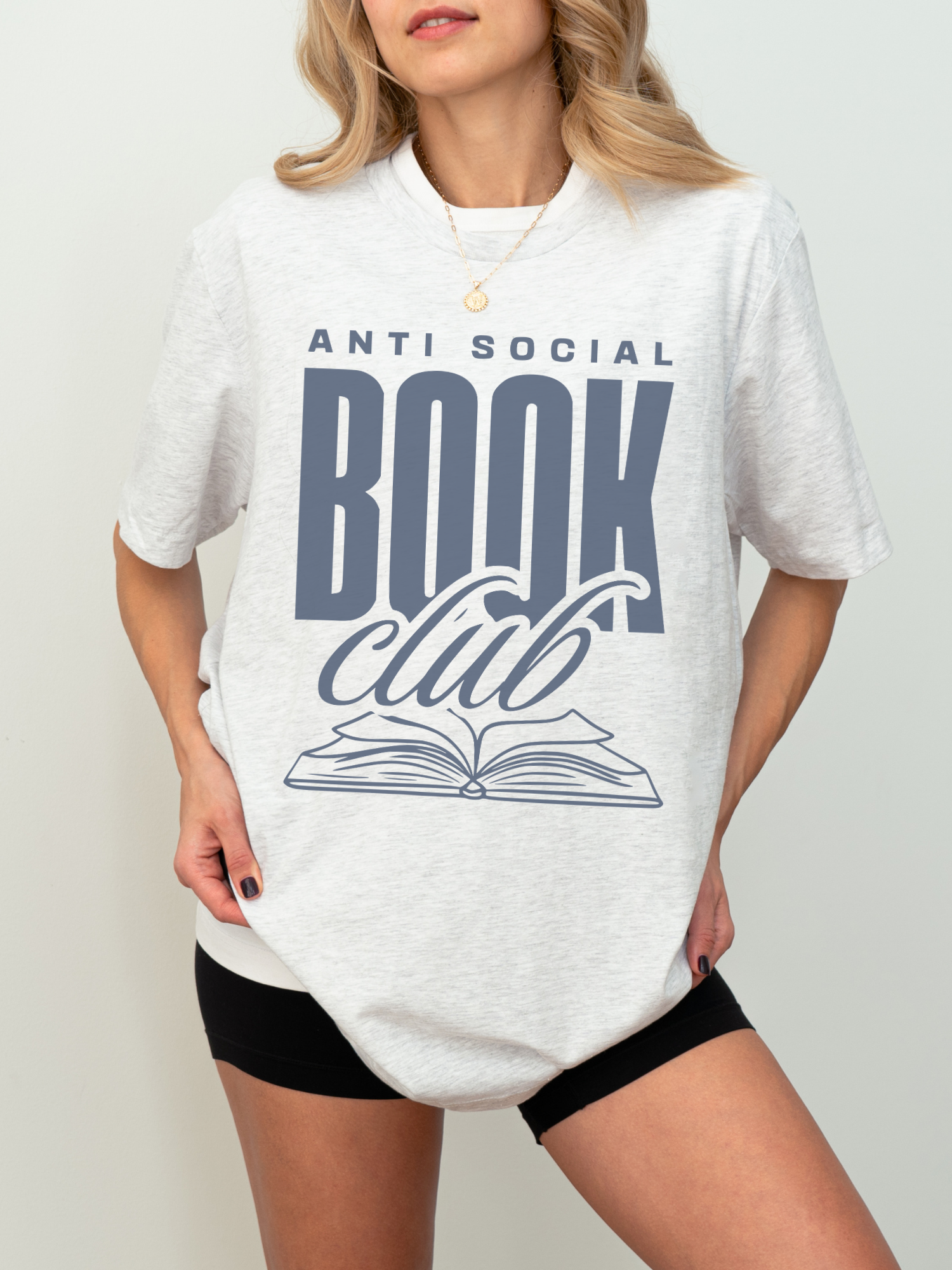 woman wearing a light grey book club t-shirt with navy blue anti social book club text and open book art
