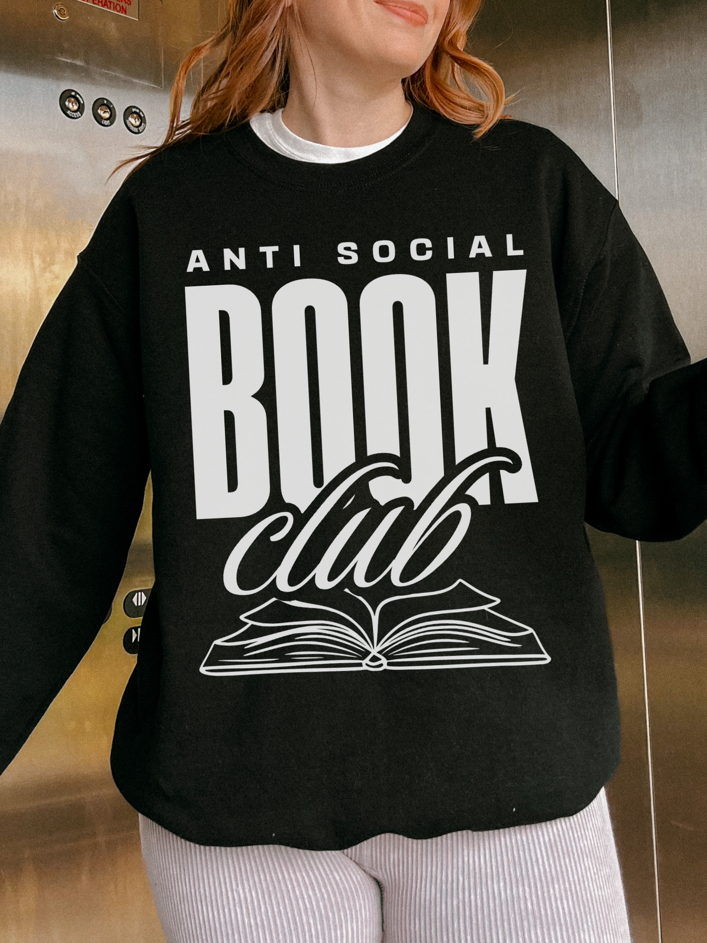 woman wearing black sweatshirt with white anti social book club text standing inside elevator