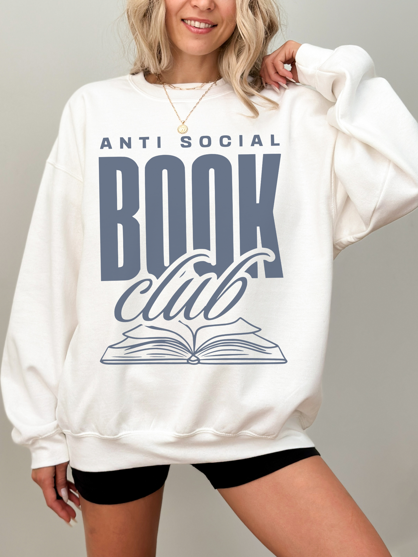 woman in white sweatshirt with anti social book club graphic in large blue serif letters