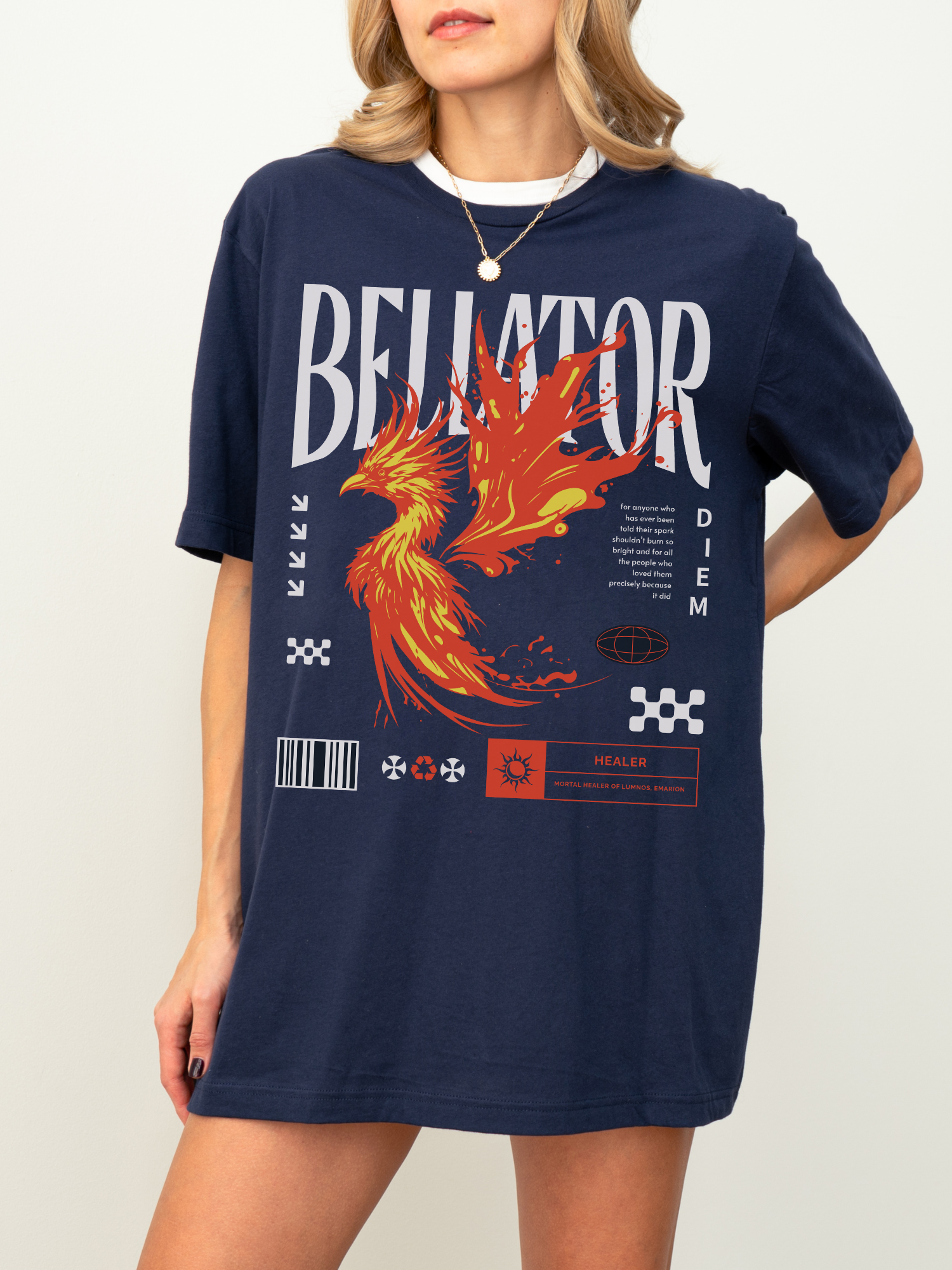 Woman wearing navy blue Bellator fantasy t-shirt with a vivid orange and red phoenix design and magical symbols, styled with a white undershirt and gold necklace, against a light background.