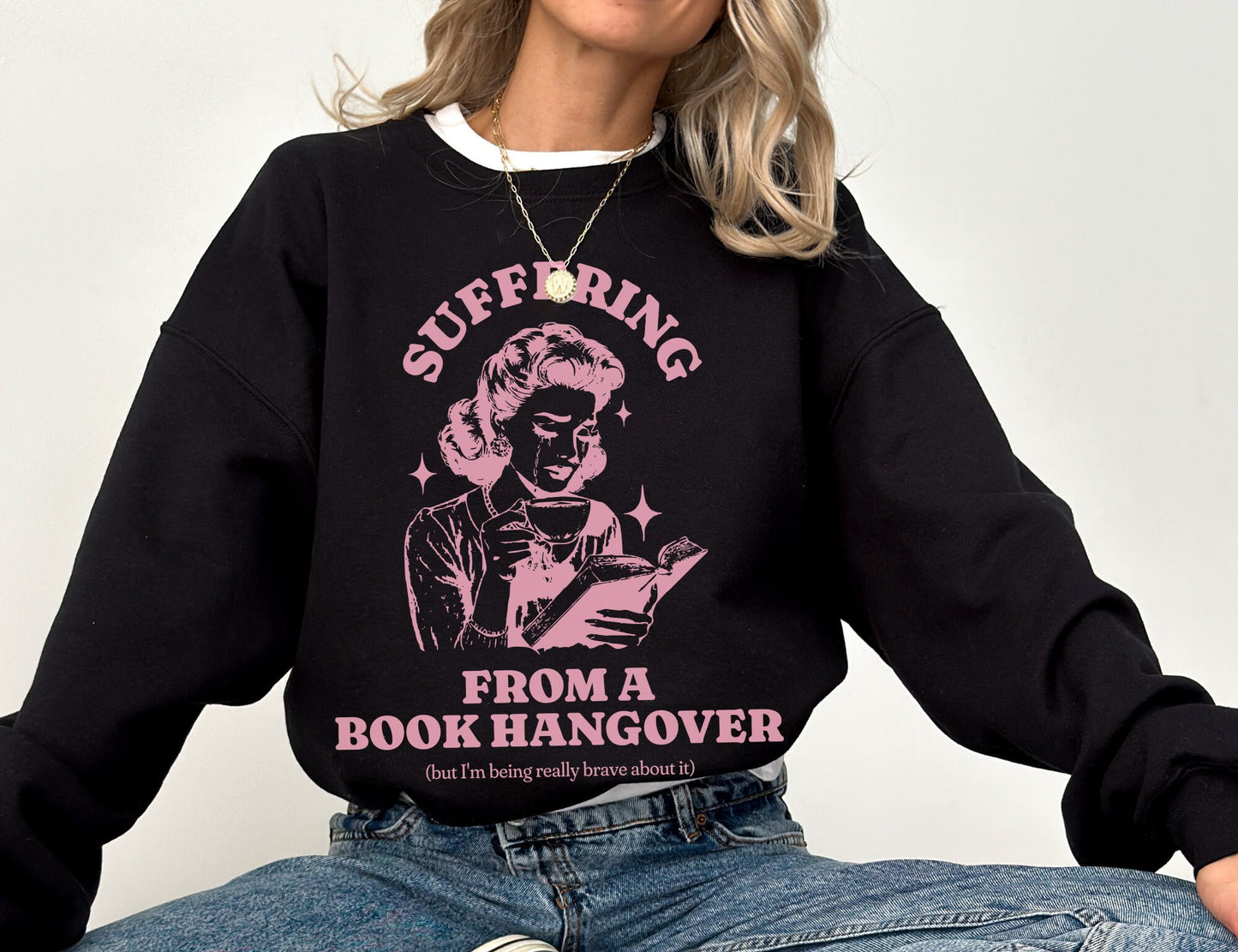 woman in black bookish sweatshirt with pink retro illustration and bold book hangover message