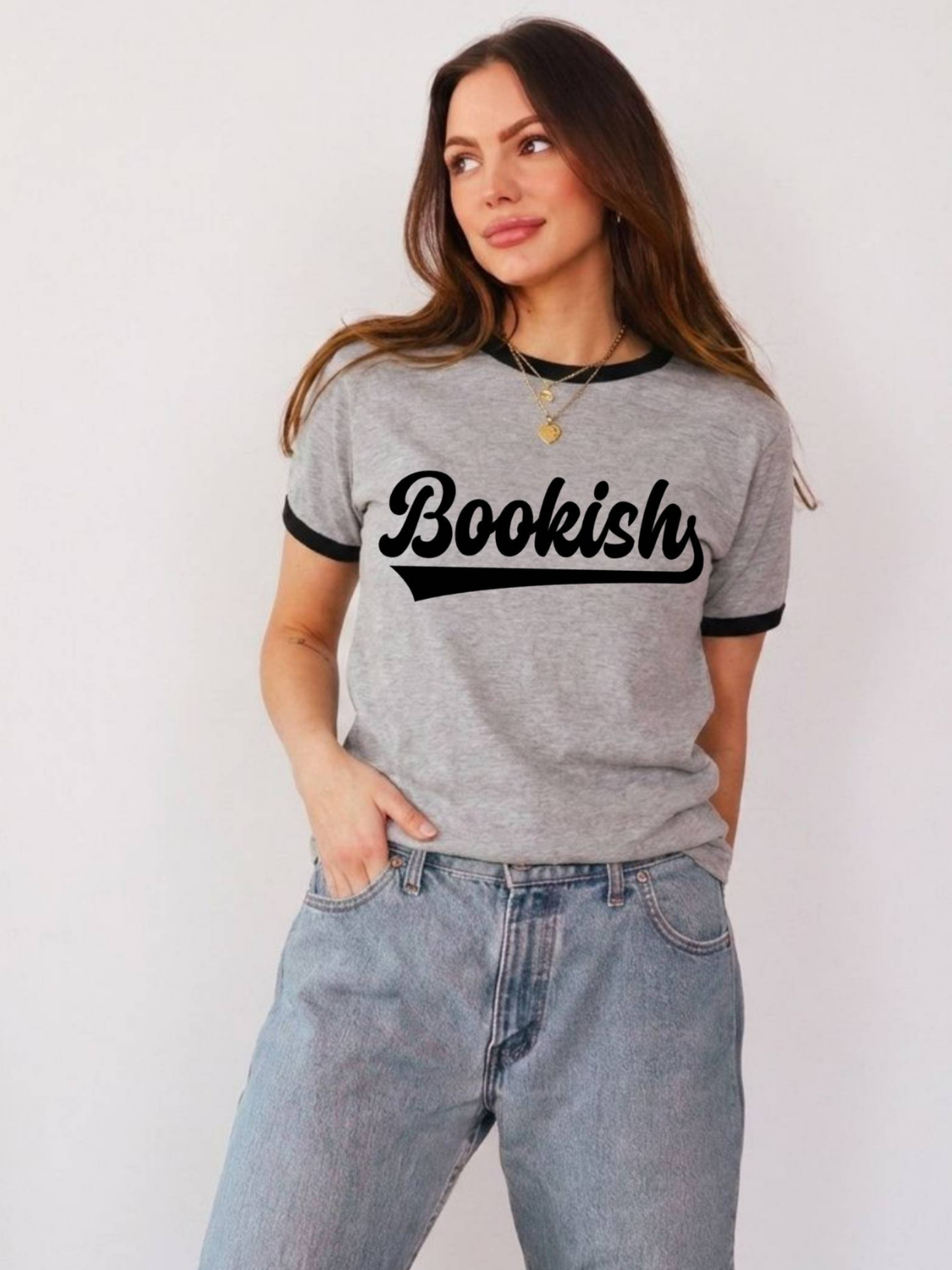 woman wearing grey and black ringer tee with bold bookish text graphic styled with relaxed denim jeans for book lover outfit