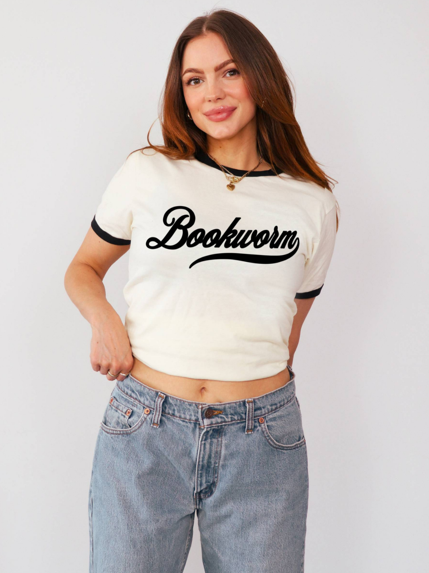 woman wearing ivory and black cropped ringer t shirt with bookworm script graphic and light wash jeans for trendy reader style
