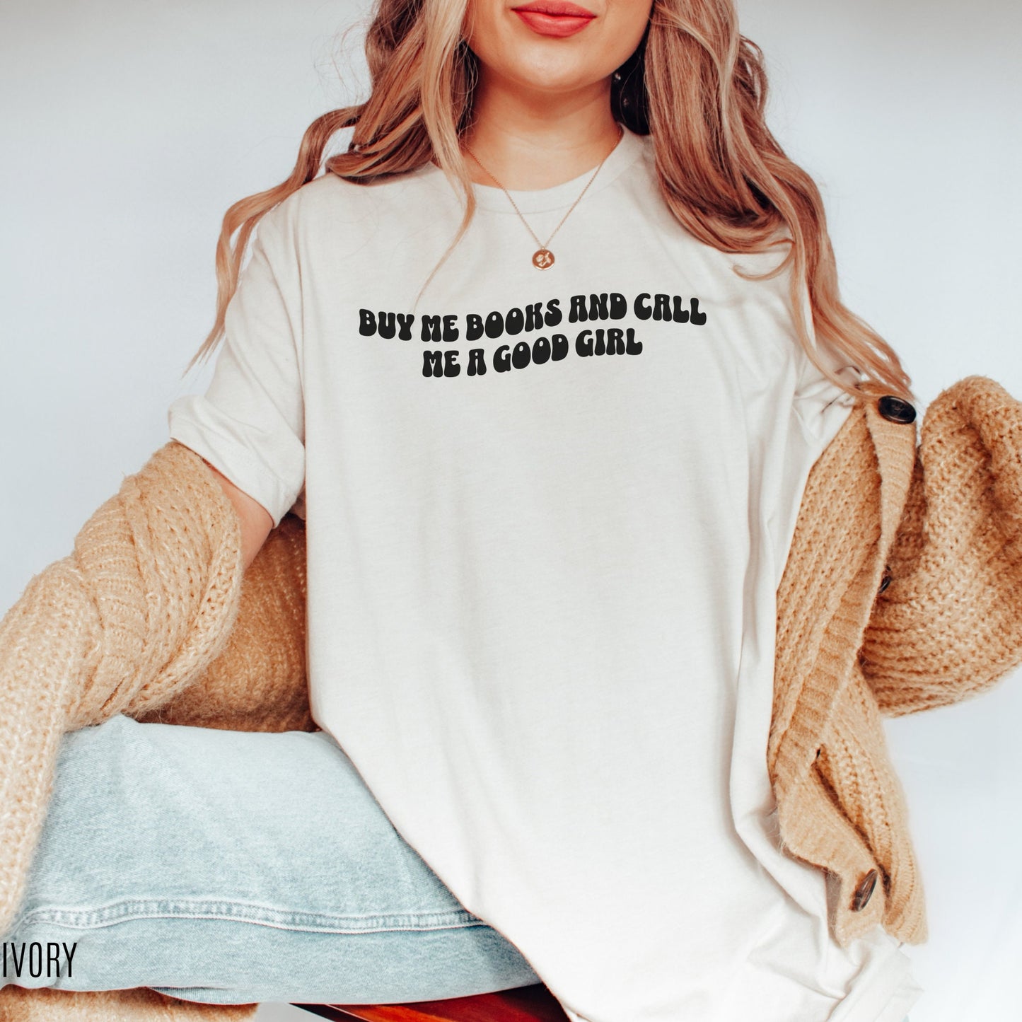 woman wearing ivory shirt that says buy me books and call me a good girl with cardigan and jeans