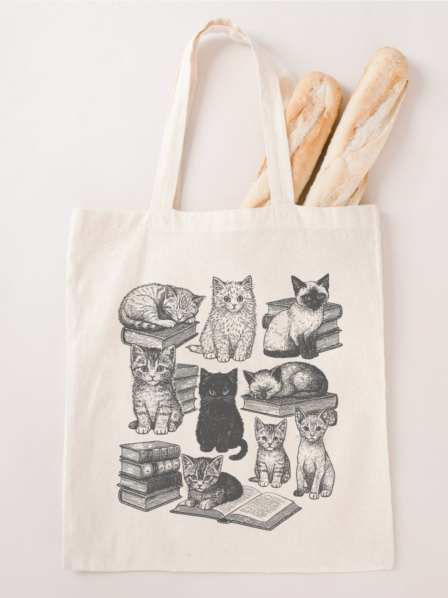 canvas tote bag with cats and books design used as grocery bag, styled with baguettes and cozy aesthetic