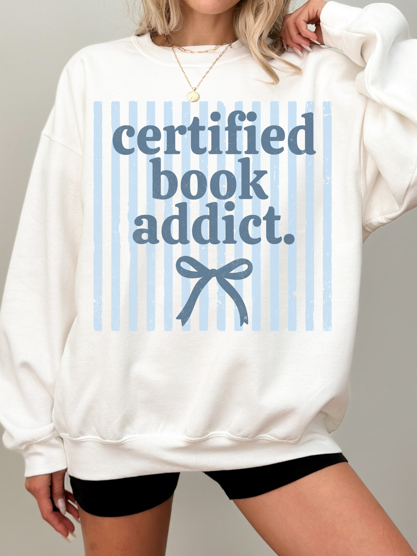 model wearing certified book addict oversized white sweatshirt with blue stripe design and bow detail styled with shorts