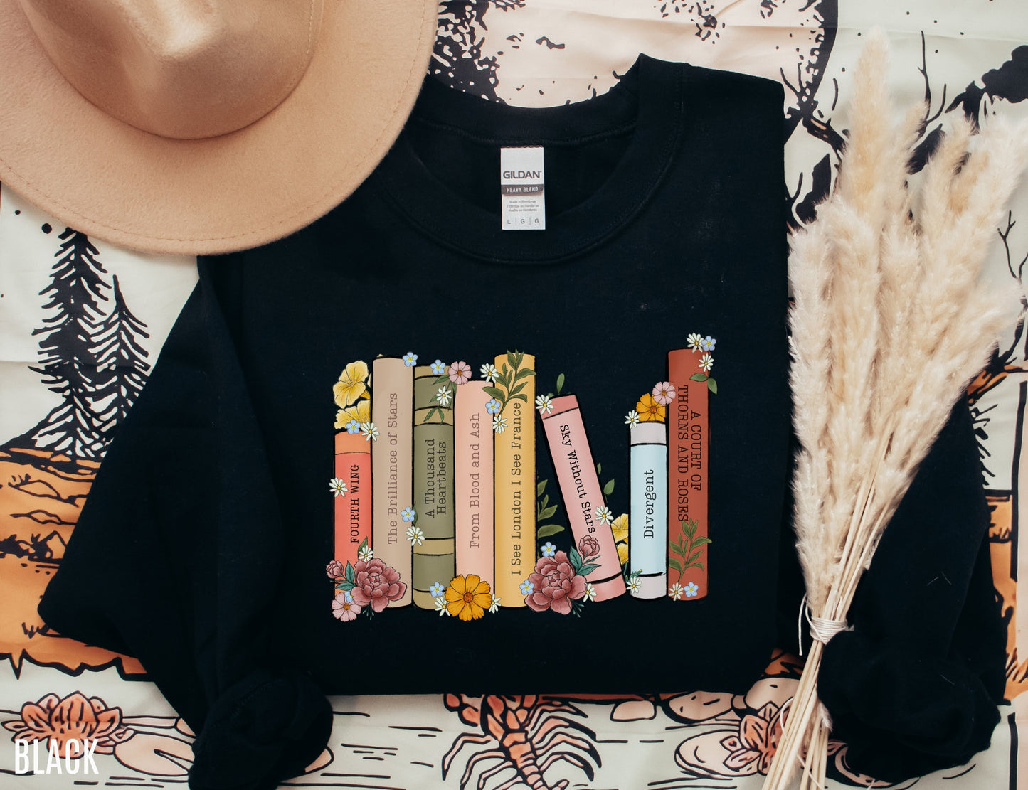 folded black sweatshirt with colorful bookshelf of fantasy and YA titles decorated with flowers