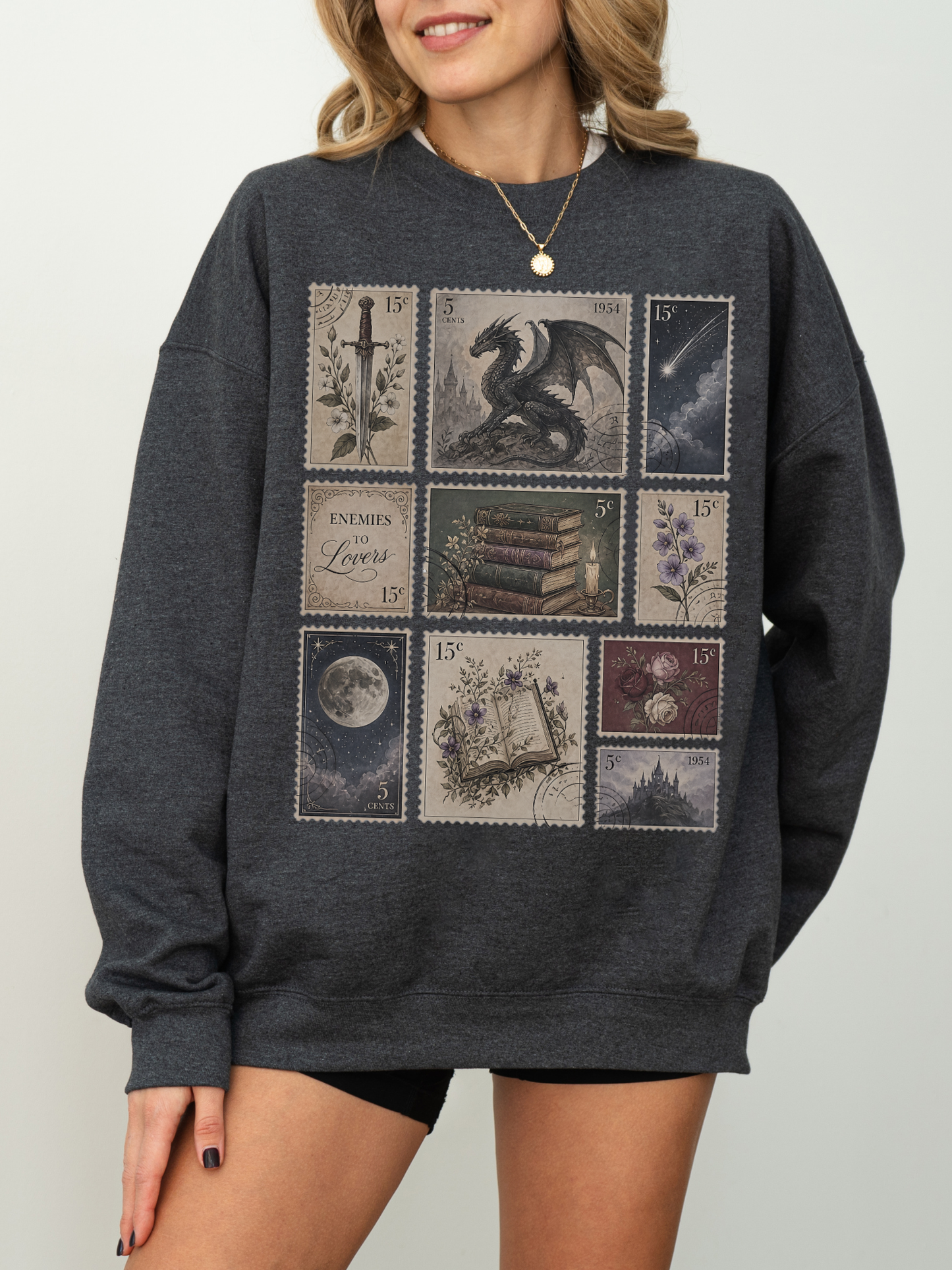 Woman wearing dark heather gray sweatshirt with fantasy postage stamp collage including dragon castle moon antique books flowers and romantic fantasy inspired artwork