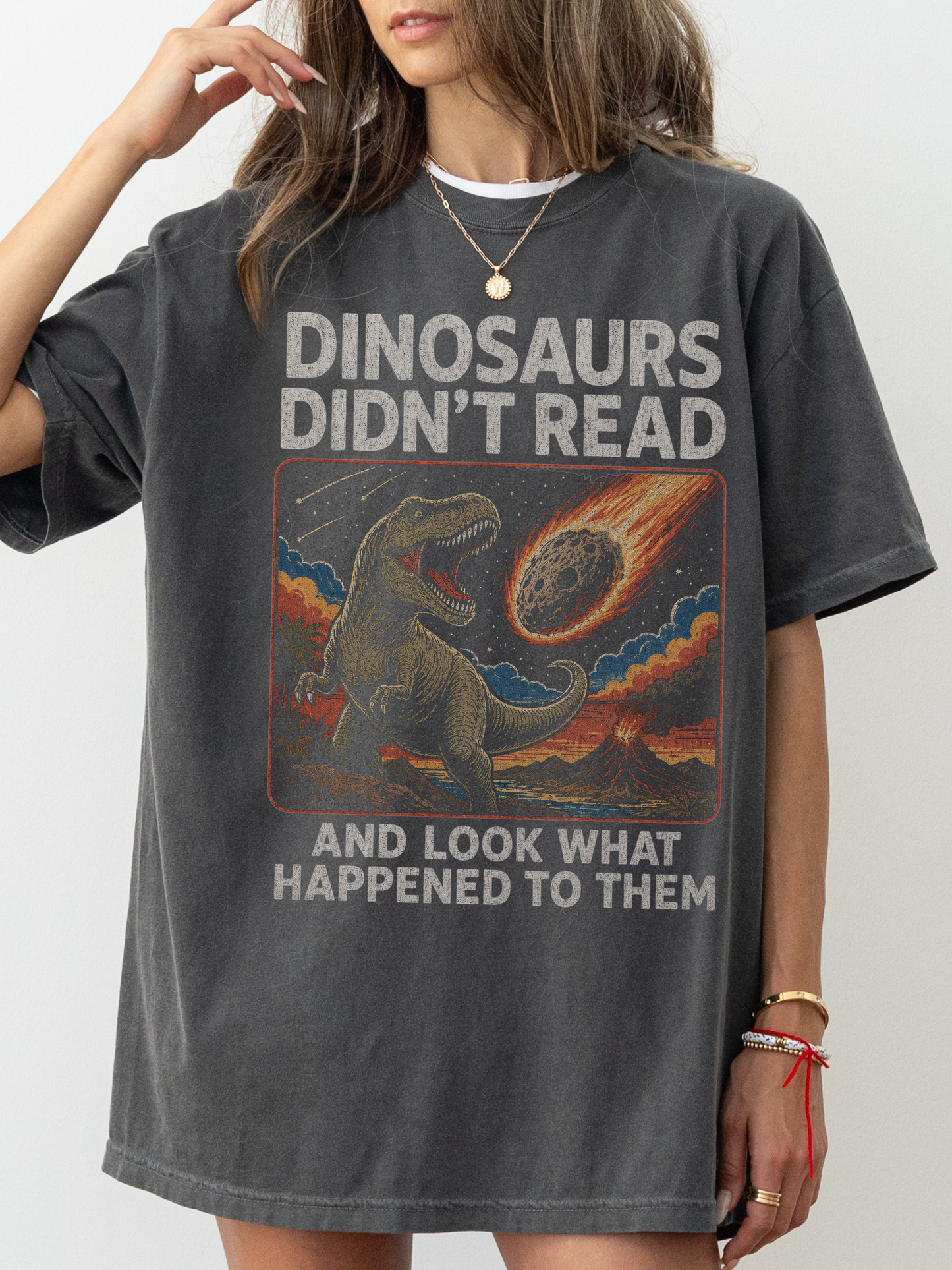 Woman wearing a pepper oversized t shirt with funny dinosaur graphic and text dinosaurs didnt read and look what happened to them meteor illustration