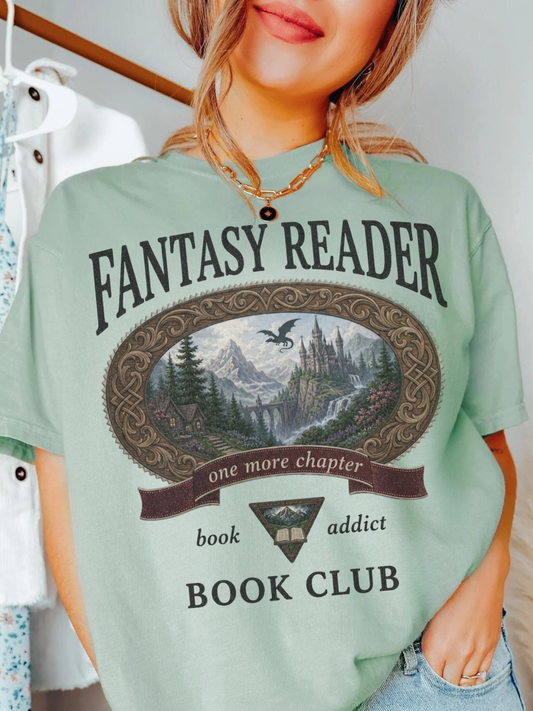 woman wearing a bay Comfort Colors Fantasy Reader Book Club shirt featuring a fantasy castle, dragon, mountains, and one more chapter design for fantasy book lovers
