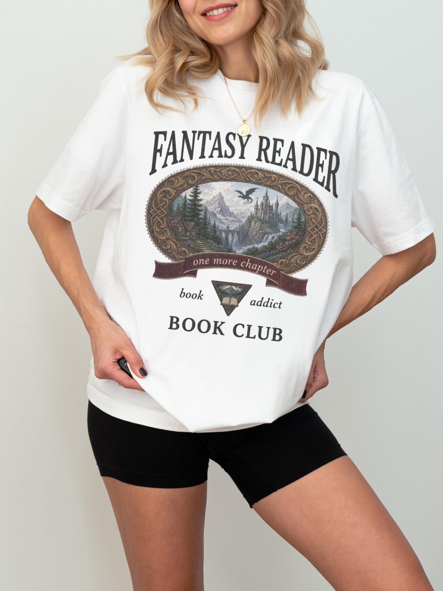 woman wearing a white Comfort Colors Fantasy Reader Book Club shirt featuring a fantasy castle, dragon, mountain scenery, and one more chapter design for fantasy book lovers and book club members