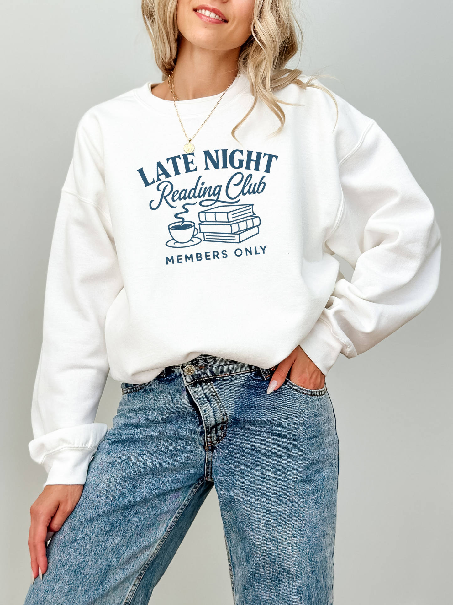 woman wearing a white sweatshirt that says late night reading club members only with books and a steaming mug graphic