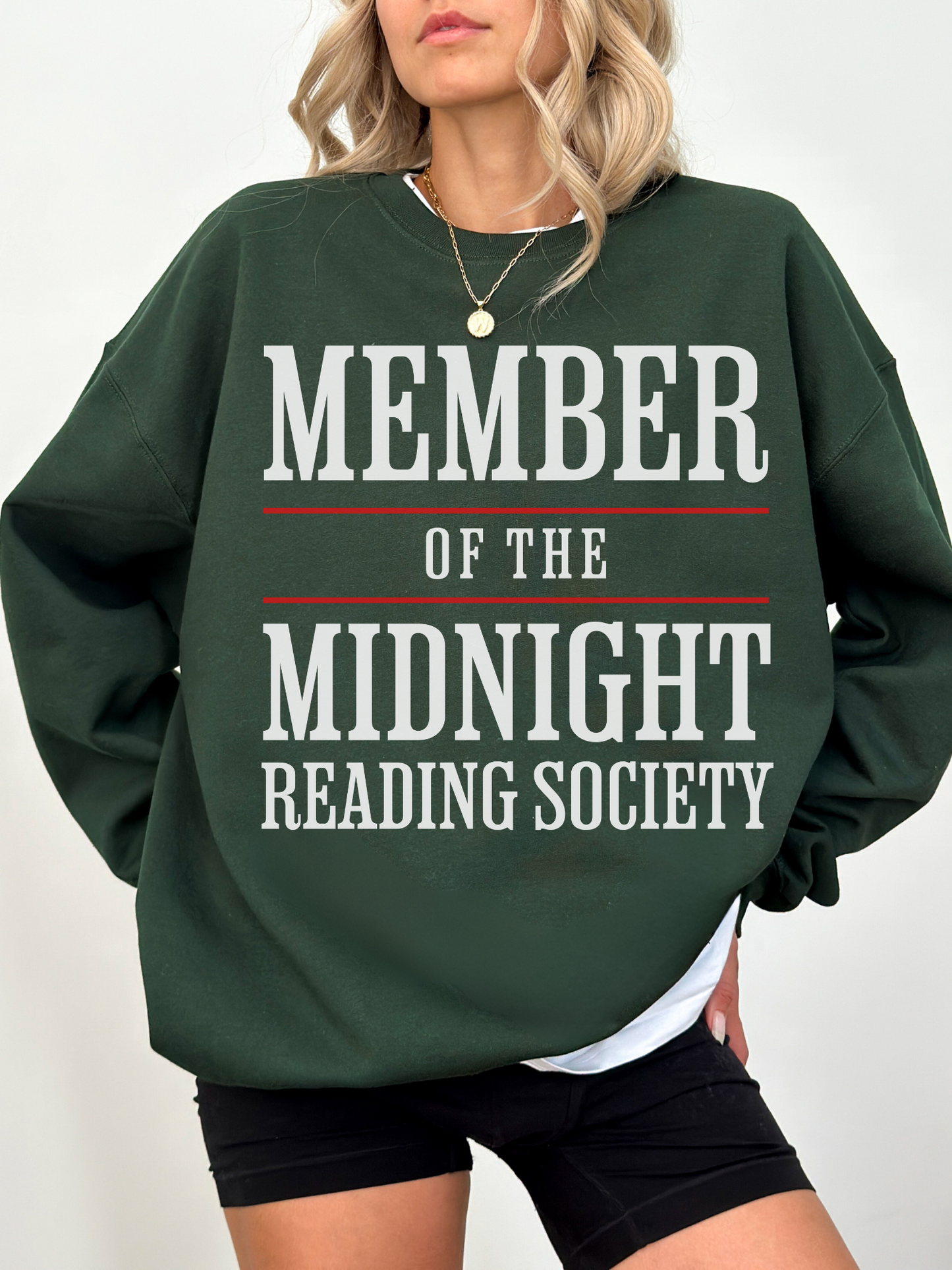 woman wearing a forest green sweatshirt with member of the midnight reading society in large white and red print