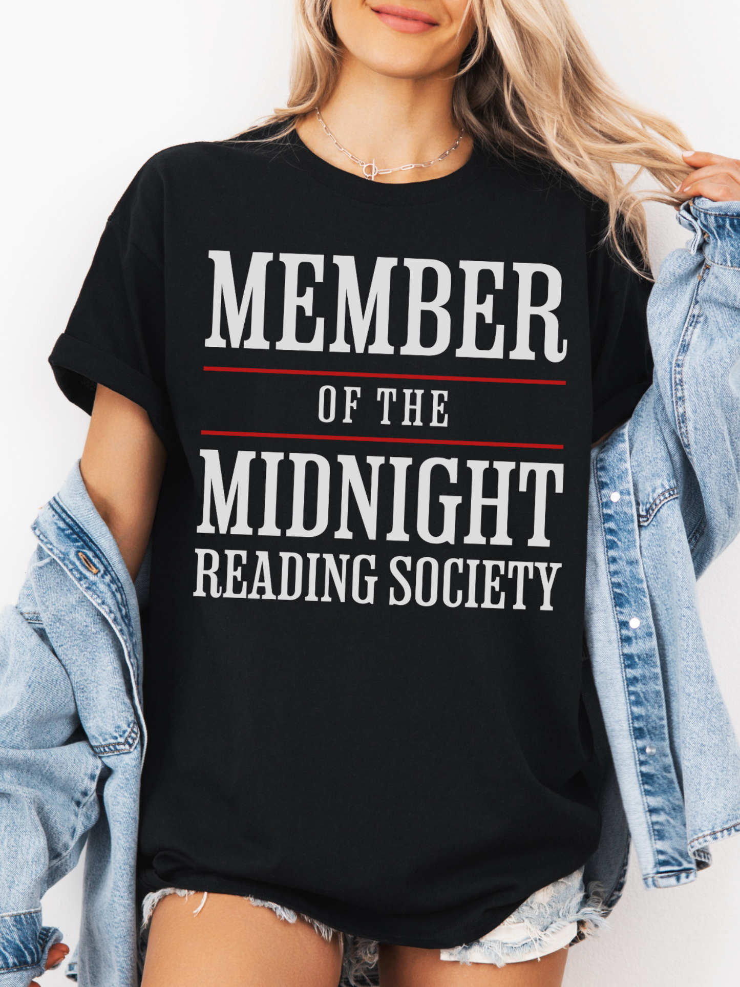 woman wearing a black t-shirt that says member of the midnight reading society in white and red block letters