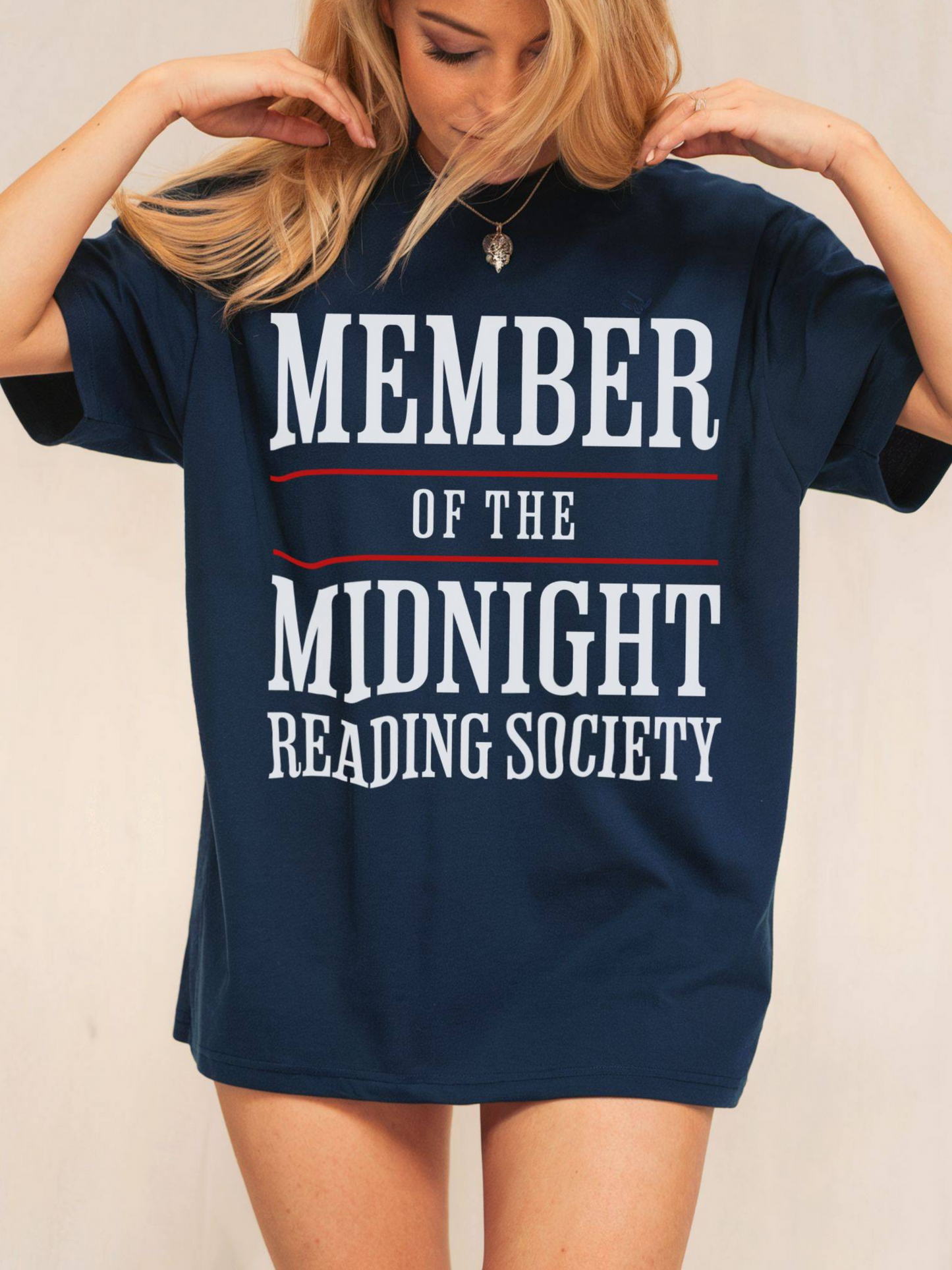 woman wearing a navy tee that says member of the midnight reading society in white text with bold red lines