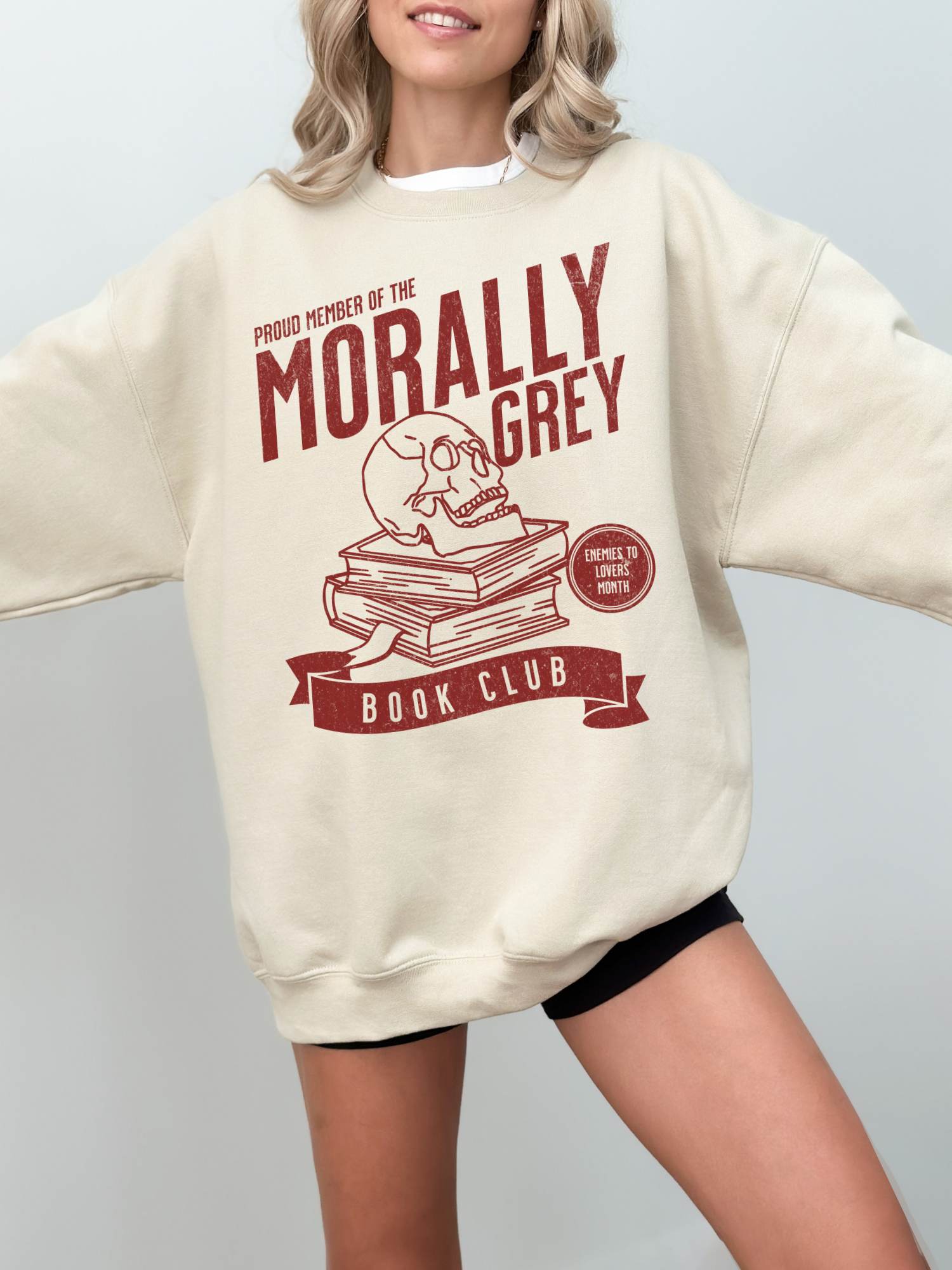 woman wearing sand sweatshirt with red morally grey book club graphic and enemies to lovers motif
