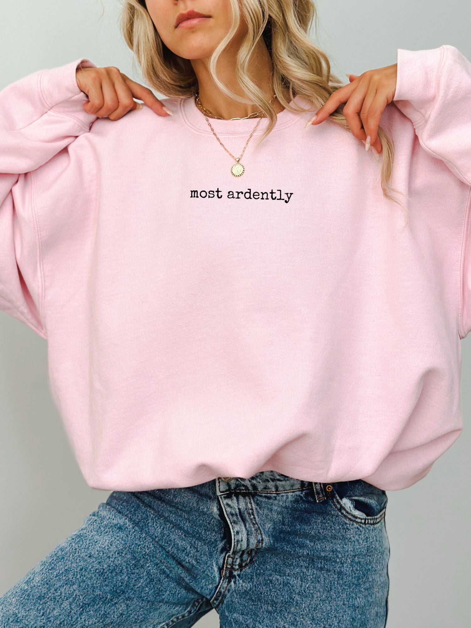 woman wearing pink sweatshirt with black minimalist most ardently text from Pride and Prejudice
