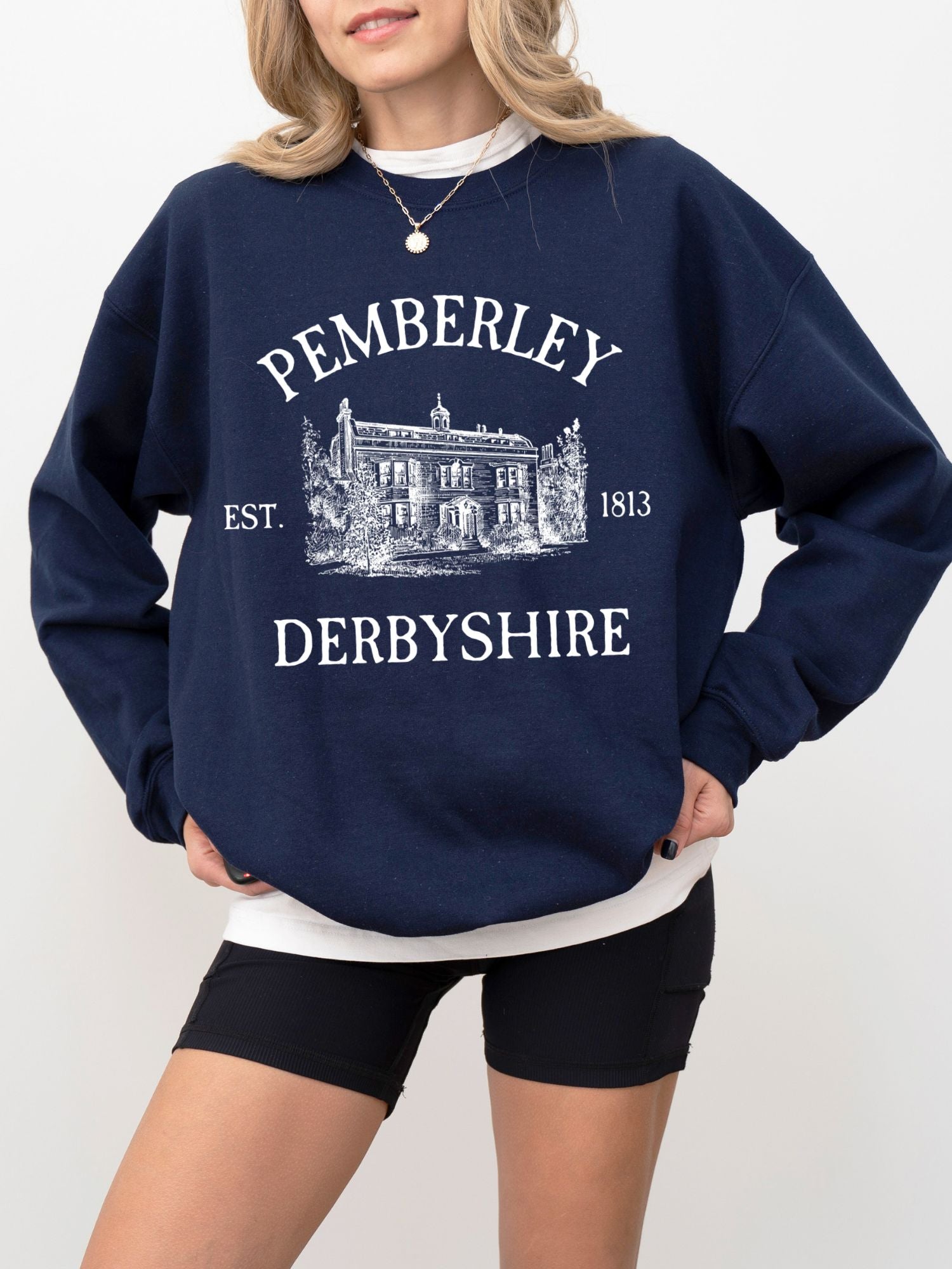 woman wearing navy sweatshirt with white Pemberley Derbyshire illustration and est 1813 text