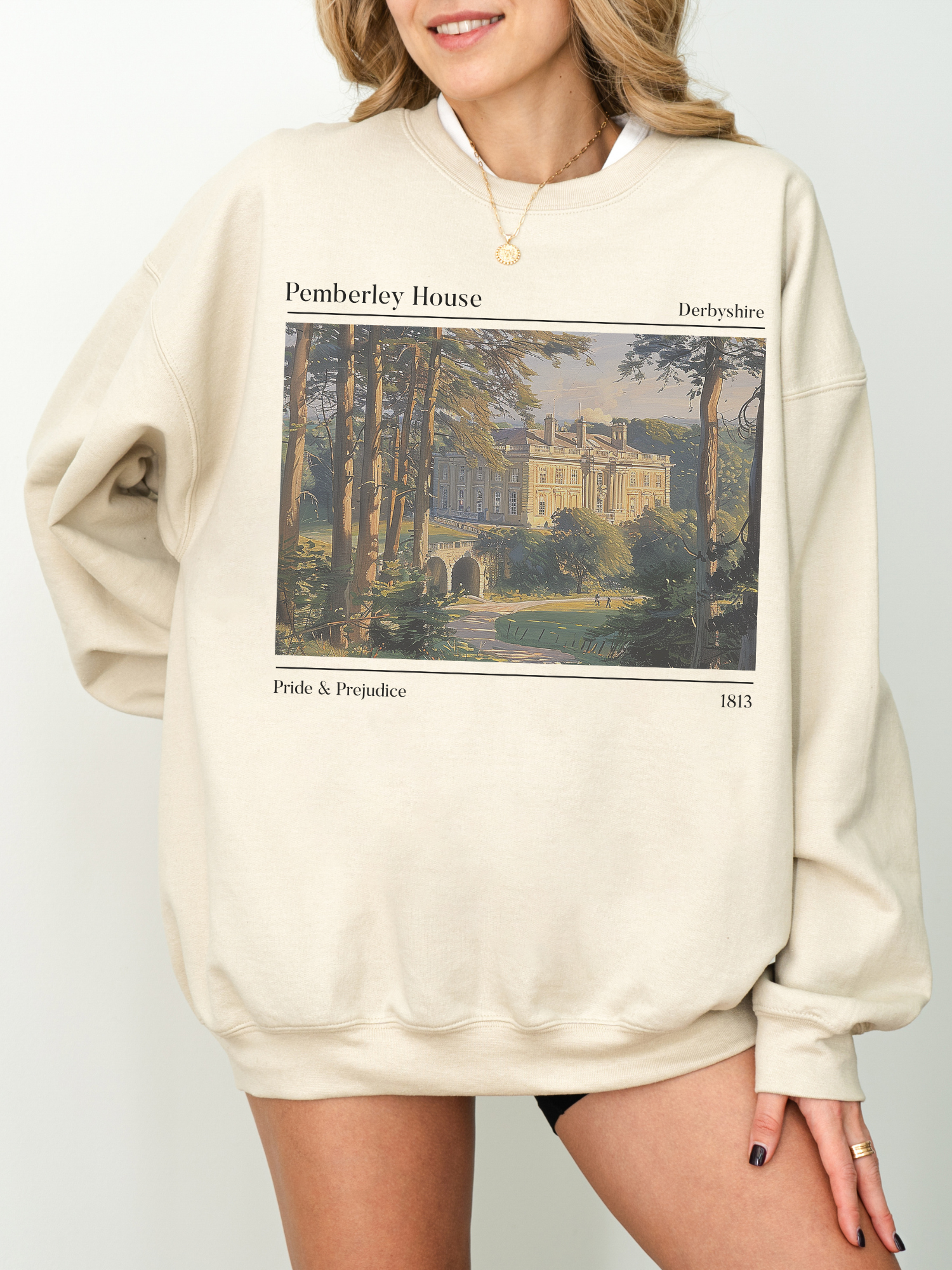 woman in sand-colored sweatshirt with Pemberley House print and Pride & Prejudice quote design