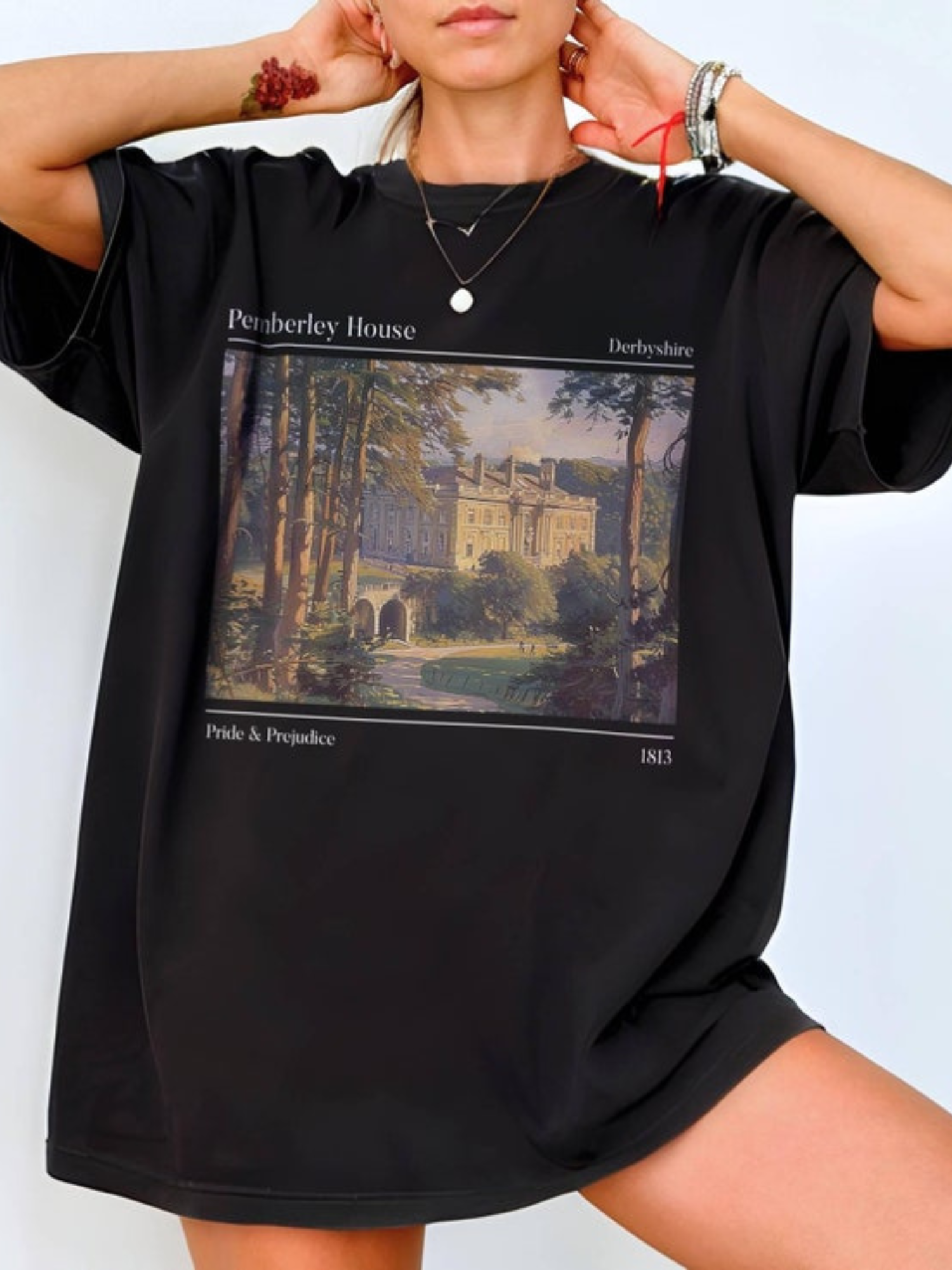 woman wearing oversized black t-shirt with romantic painting of Pemberley House and Jane Austen text