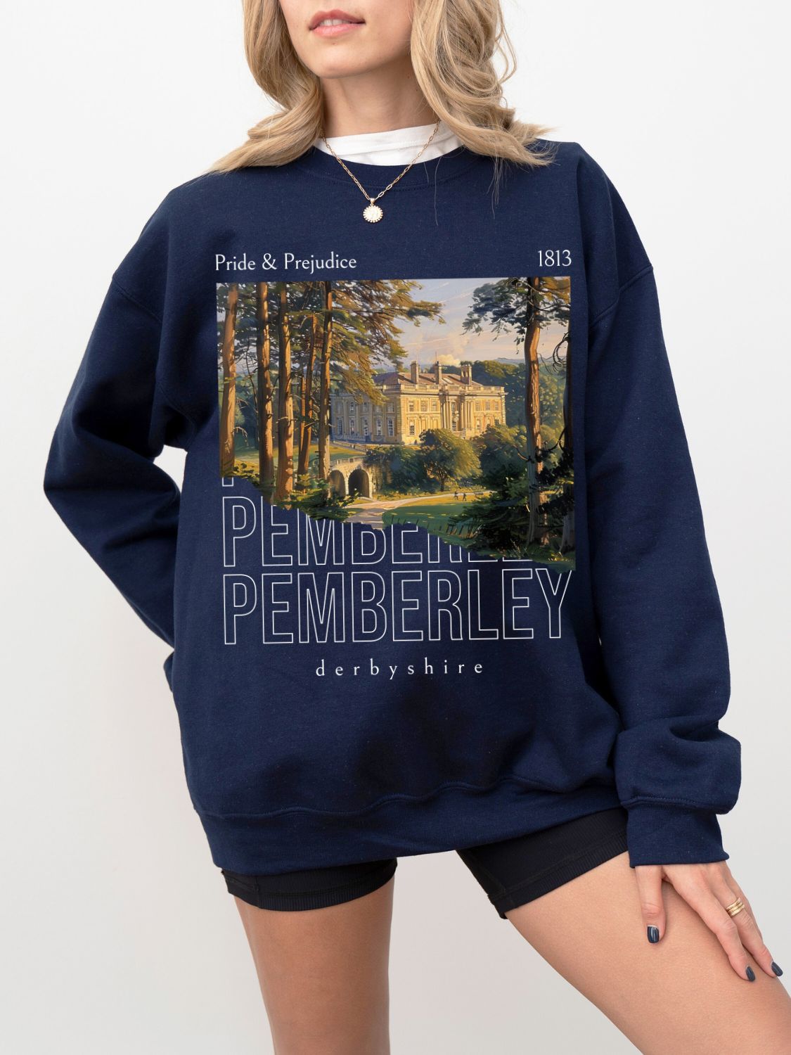 woman wearing navy Pride and Prejudice sweatshirt with illustration of Pemberley and 1813 text