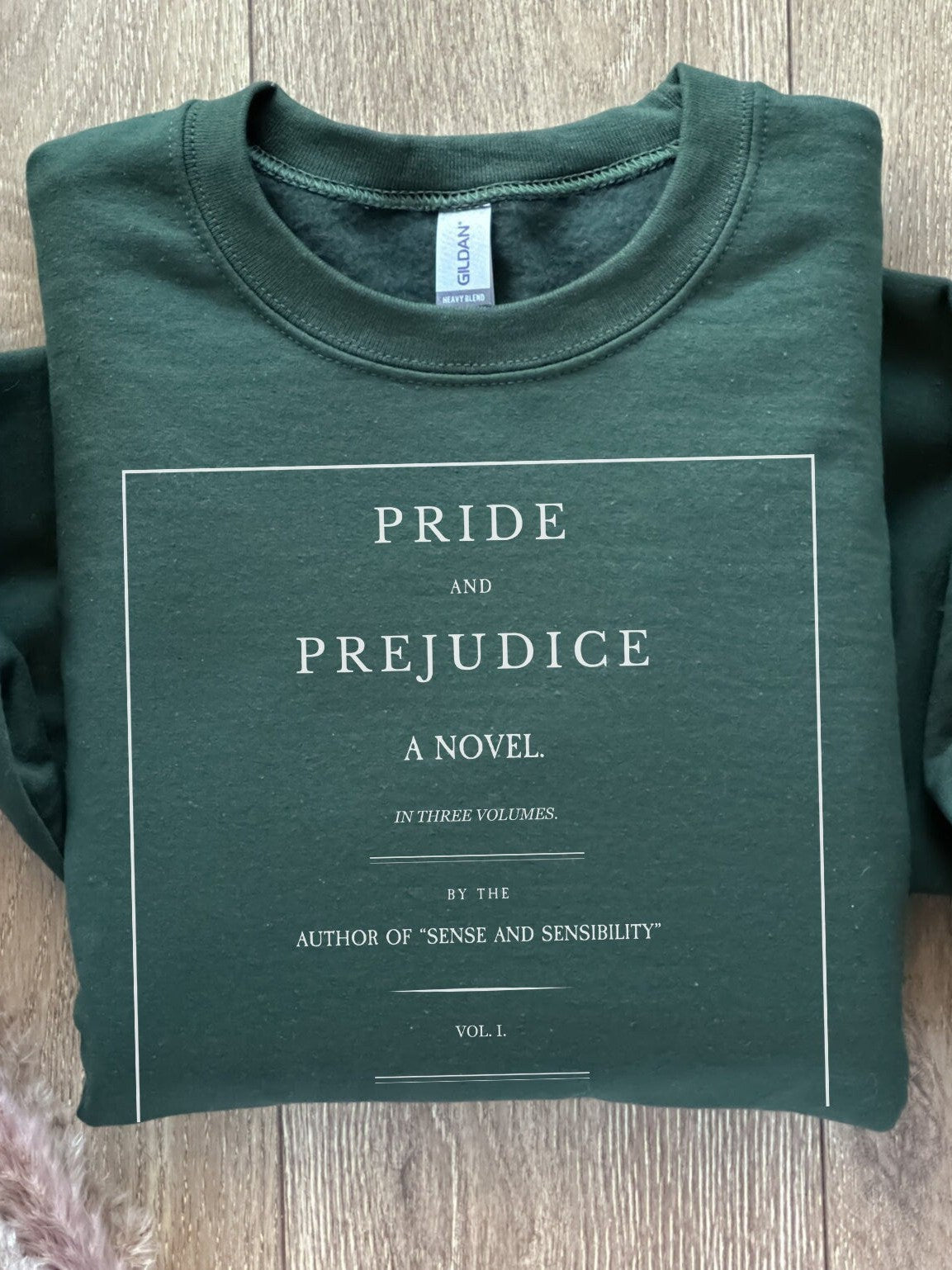 folded forest green sweatshirt with vintage Pride and Prejudice book cover print in white