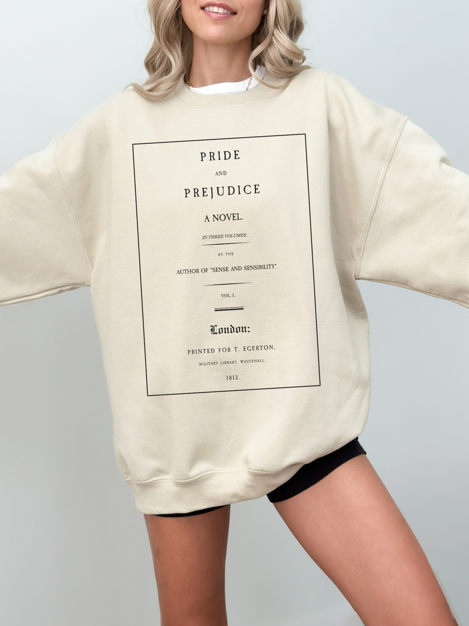 woman wearing sand-colored sweatshirt with classic Pride and Prejudice title page print in black