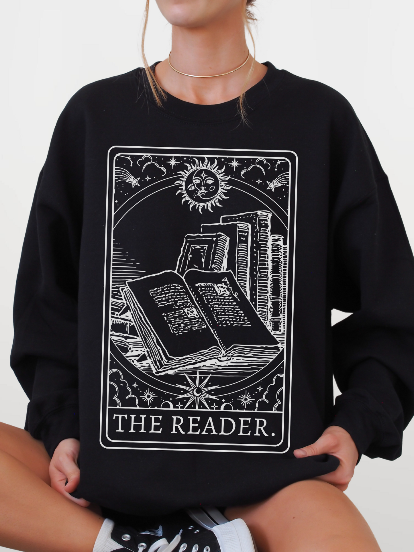 woman wearing a black sweatshirt with tarot-style book design and the words the reader on front