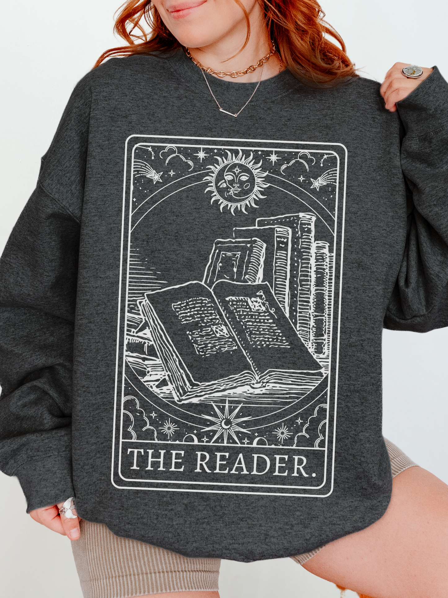 woman wearing a dark grey heather sweatshirt with celestial tarot card design and the words the reader