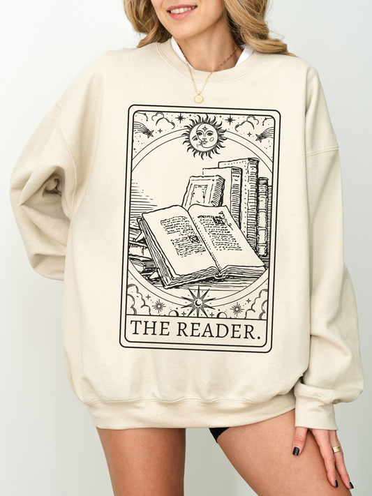 woman in beige sand-colored sweatshirt featuring book-themed tarot card and witchy sun art