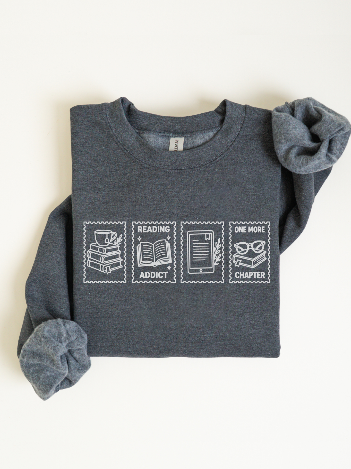 folded dark heather gray sweatshirt featuring reading addict one more chapter graphic with coffee books open book e reader and reading glasses in a postage stamp inspired layout for book lovers