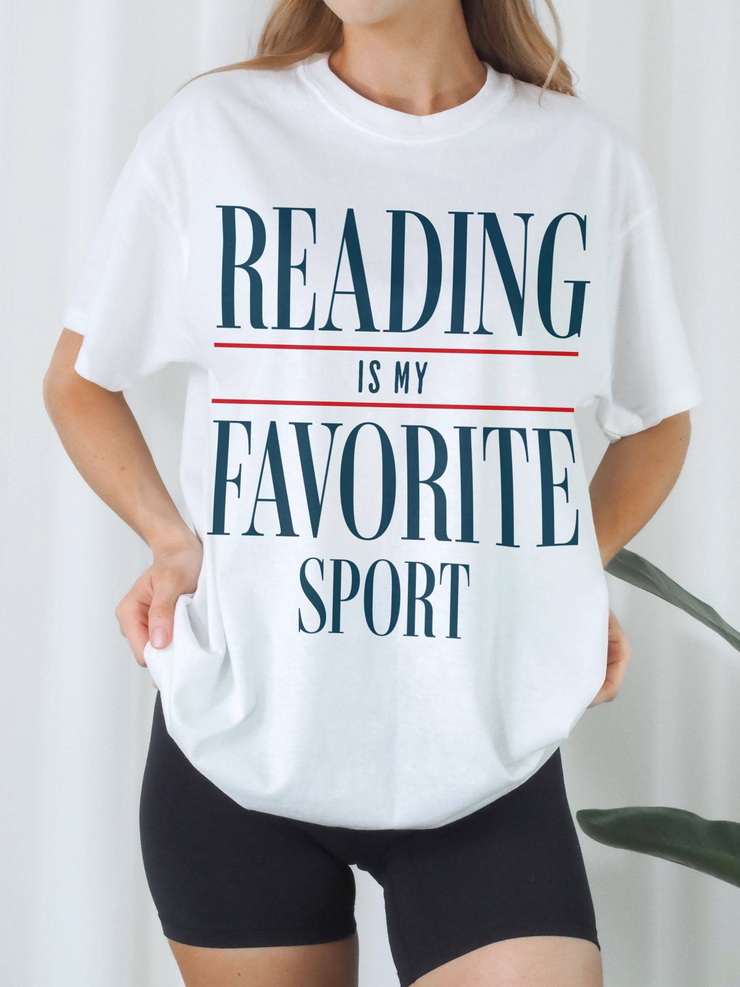 Woman wearing oversized "Reading Is My Favorite Sport" graphic tee in white with biker shorts