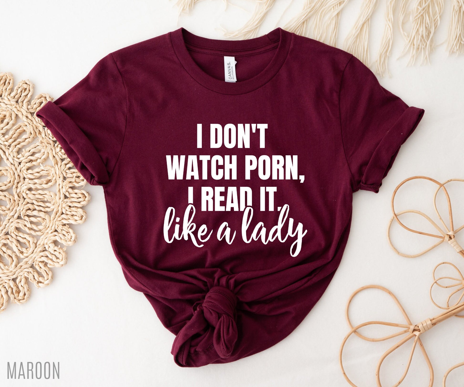 folded maroon shirt that says i don't watch porn i read it like a lady styled with macrame and rattan