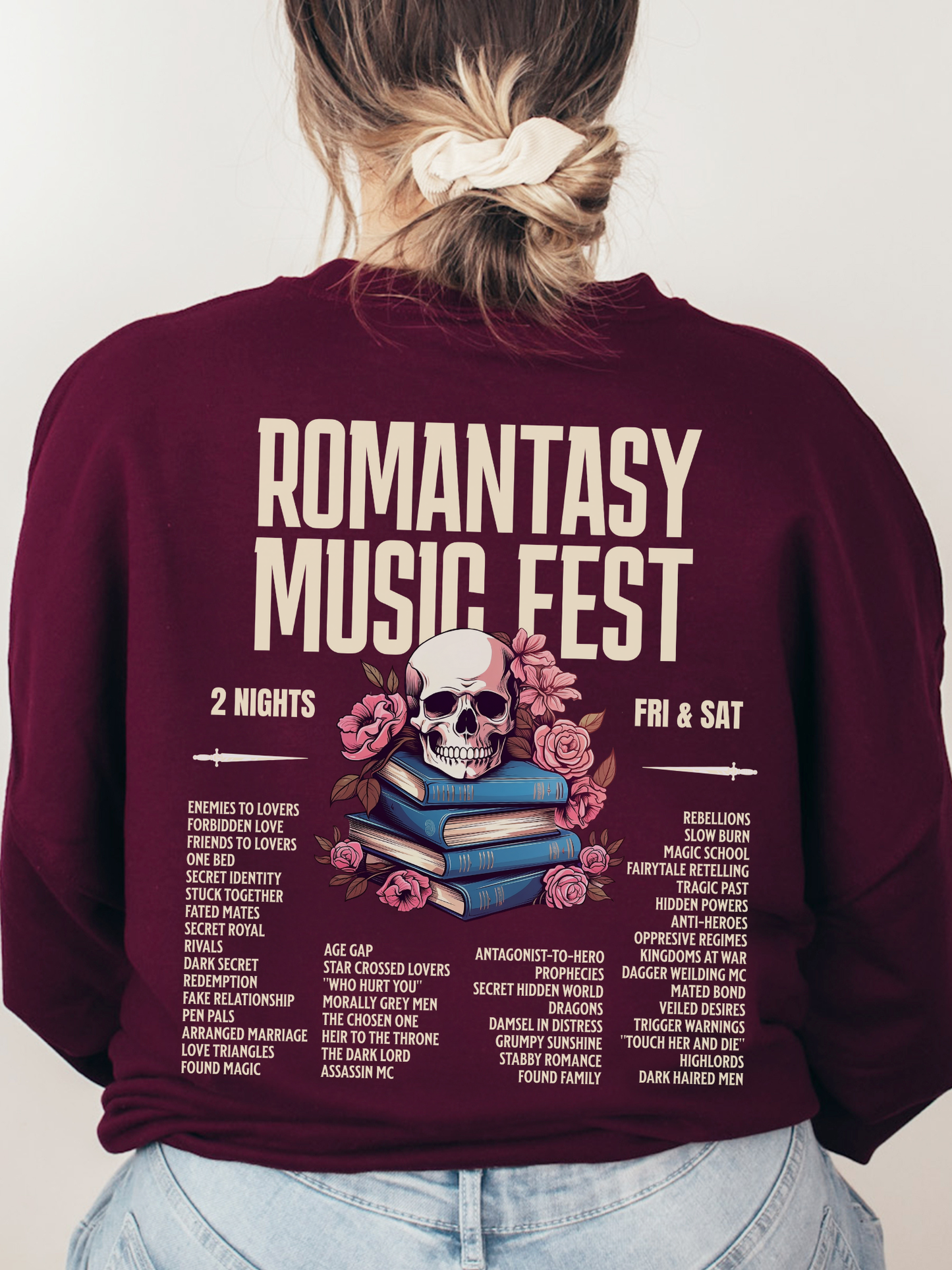 Maroon crewneck sweatshirt shown from the back with large Romantasy Music Fest print, showcasing a fantasy-inspired concert-style design with a skull, flowers, and popular romantasy tropes.