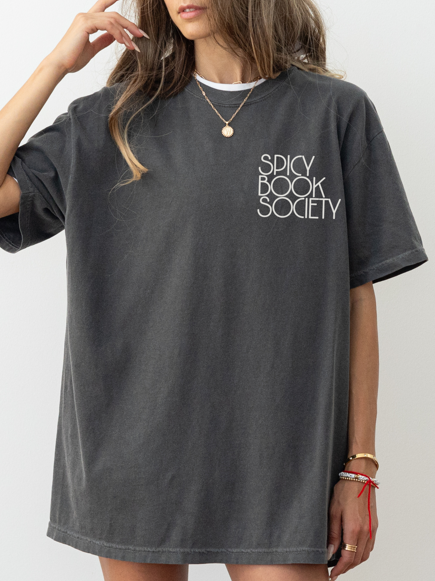 Model wearing an oversized pepper black Comfort Colors shirt with “Spicy Book Society” printed on the chest. Styled in a cozy, book-lover look with gold jewelry and relaxed pose, ideal for spicy book readers.