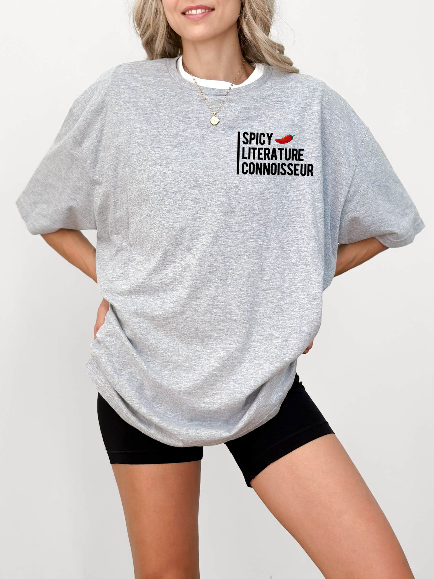 woman wearing oversized gray shirt with spicy literature connoisseur design and black biker shorts