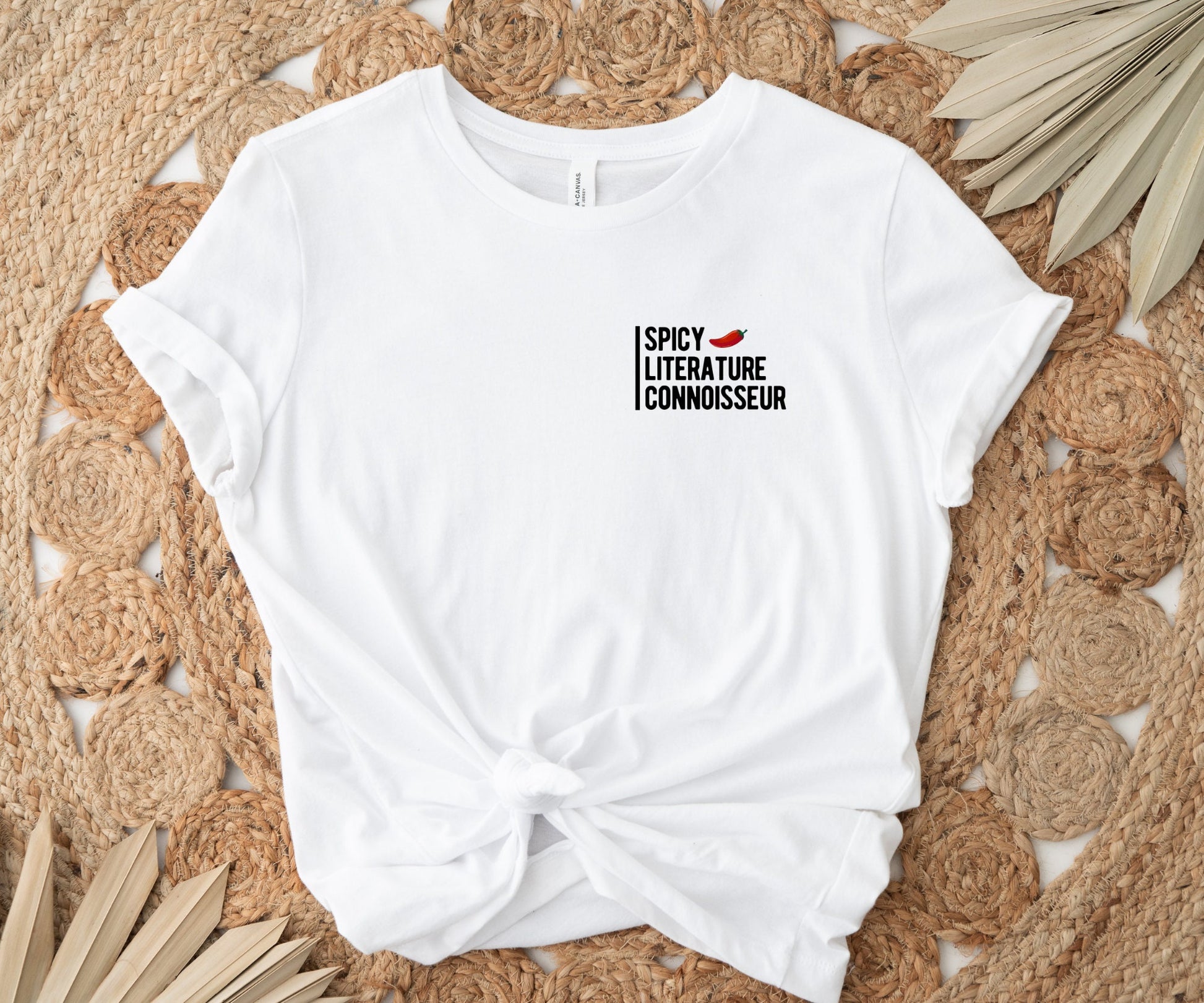 white t-shirt tied at the waist with spicy literature connoisseur design laid on woven boho rug