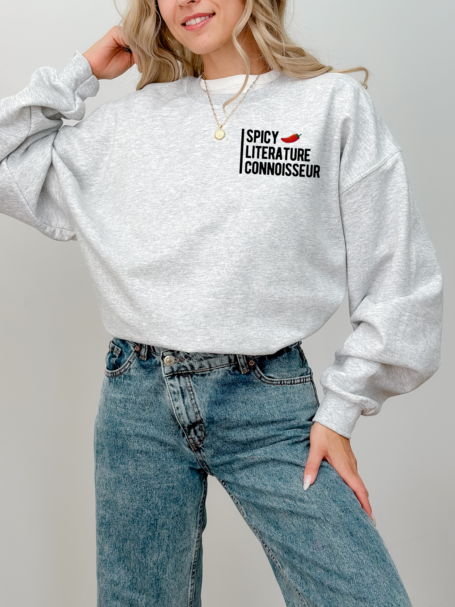 woman wearing ash grey Spicy Literature Connoisseur sweatshirt with red pepper icon, styled with jeans