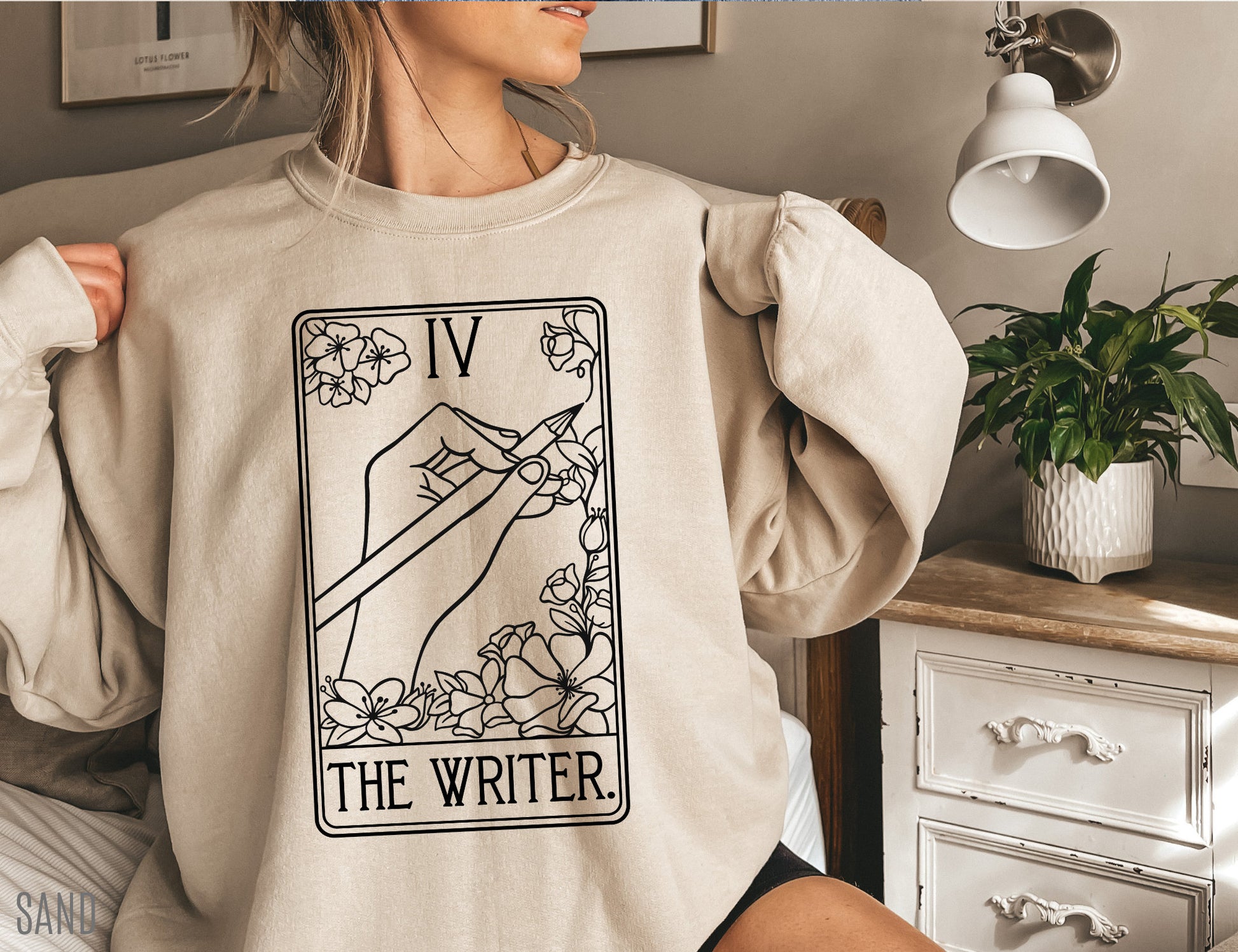 woman in cozy sand-colored sweatshirt featuring hand-drawn tarot card graphic labeled The Writer