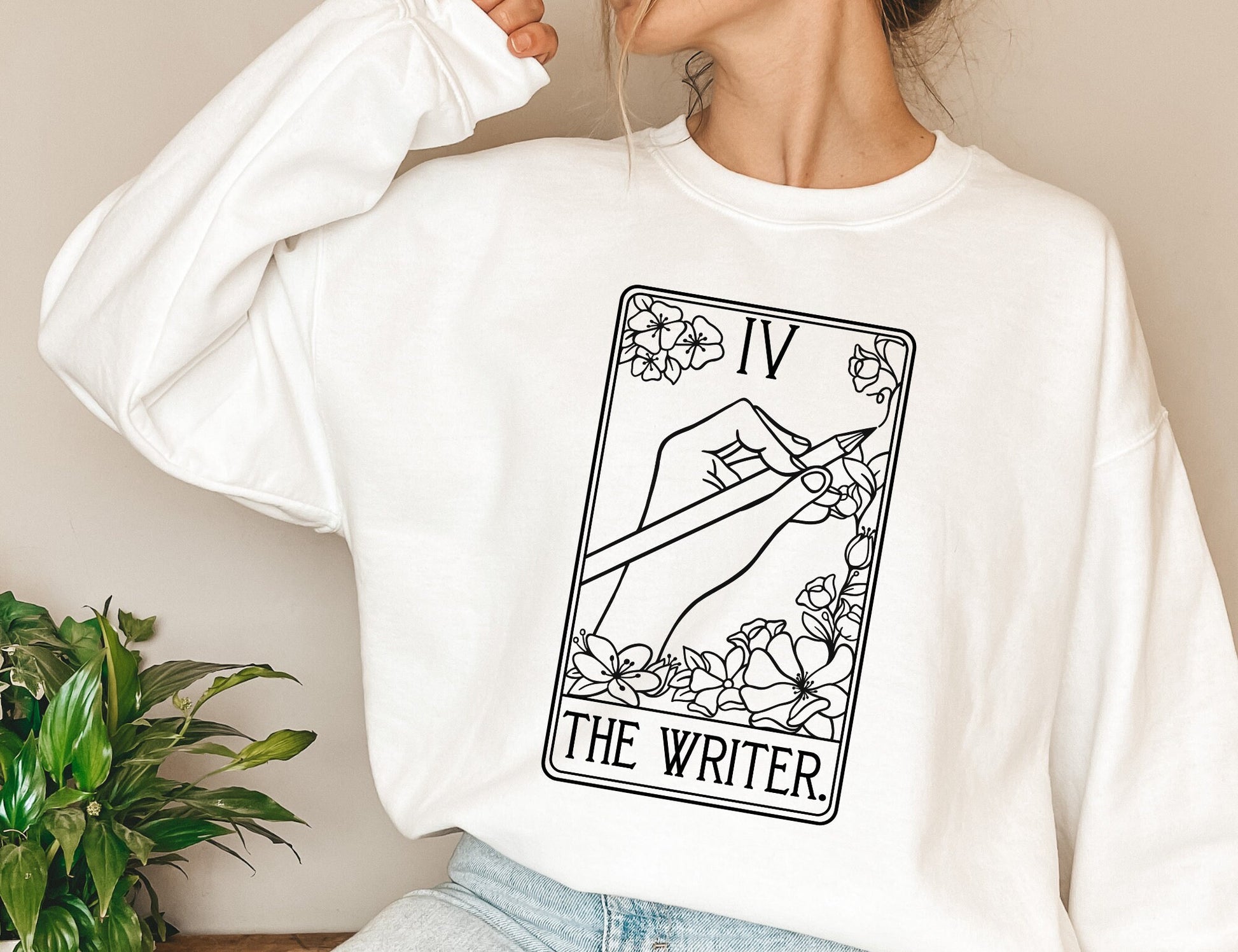 white sweatshirt with black tarot-style illustration of hand holding pencil and text The Writer