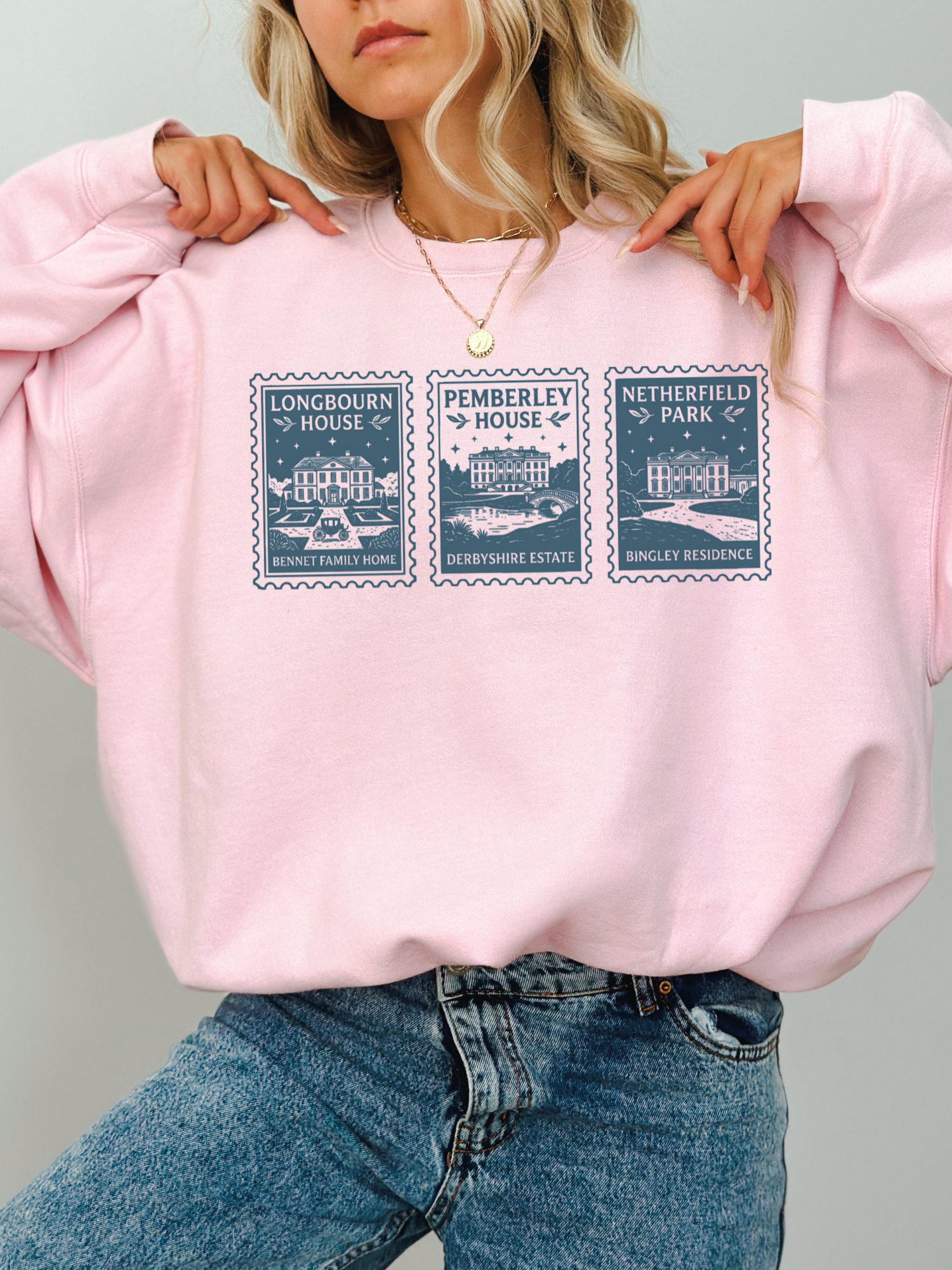 woman wearing oversized pink sweatshirt with Pride and Prejudice stamp illustrations of Longbourn House Pemberley House and Netherfield Park book lover aesthetic