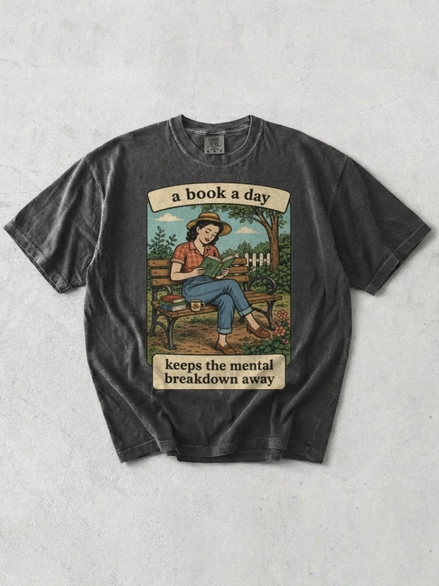 Pepper t-shirt with graphic and text 'a book a day keeps the mental breakdown away' on a textured gray background