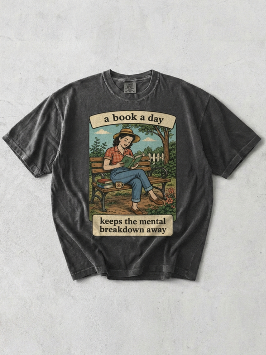 Pepper t-shirt with graphic and text 'a book a day keeps the mental breakdown away' on a textured gray background