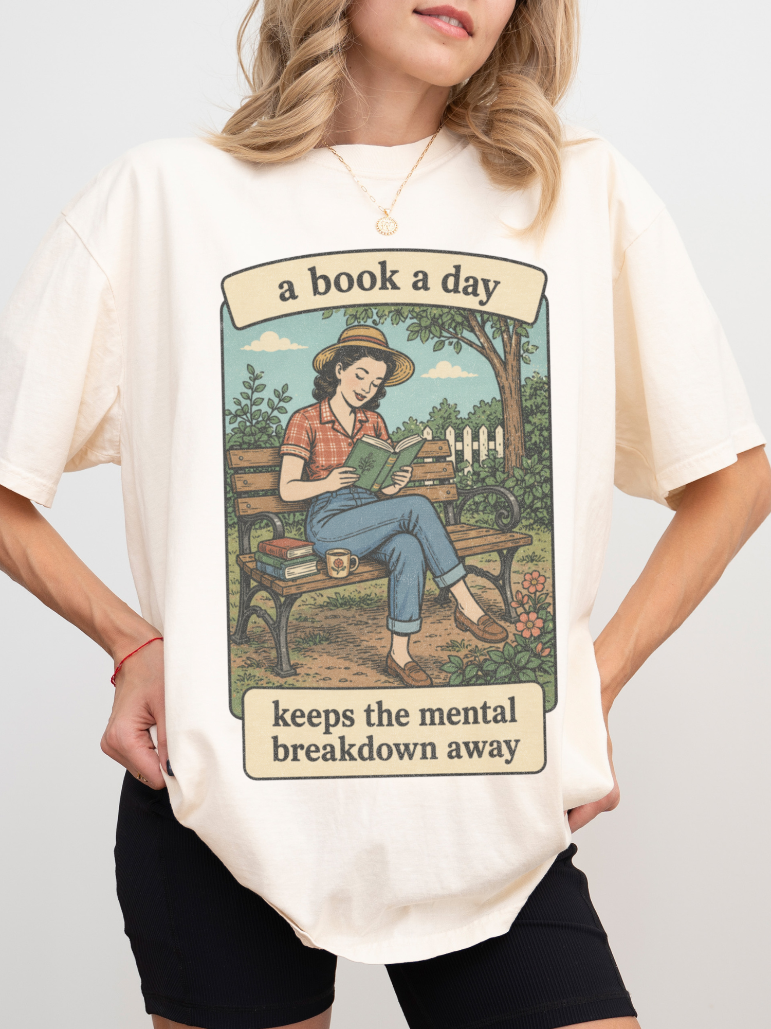 Woman wearing an ivory oversized t shirt with vintage reading illustration and text a book a day keeps the mental breakdown away styled casually