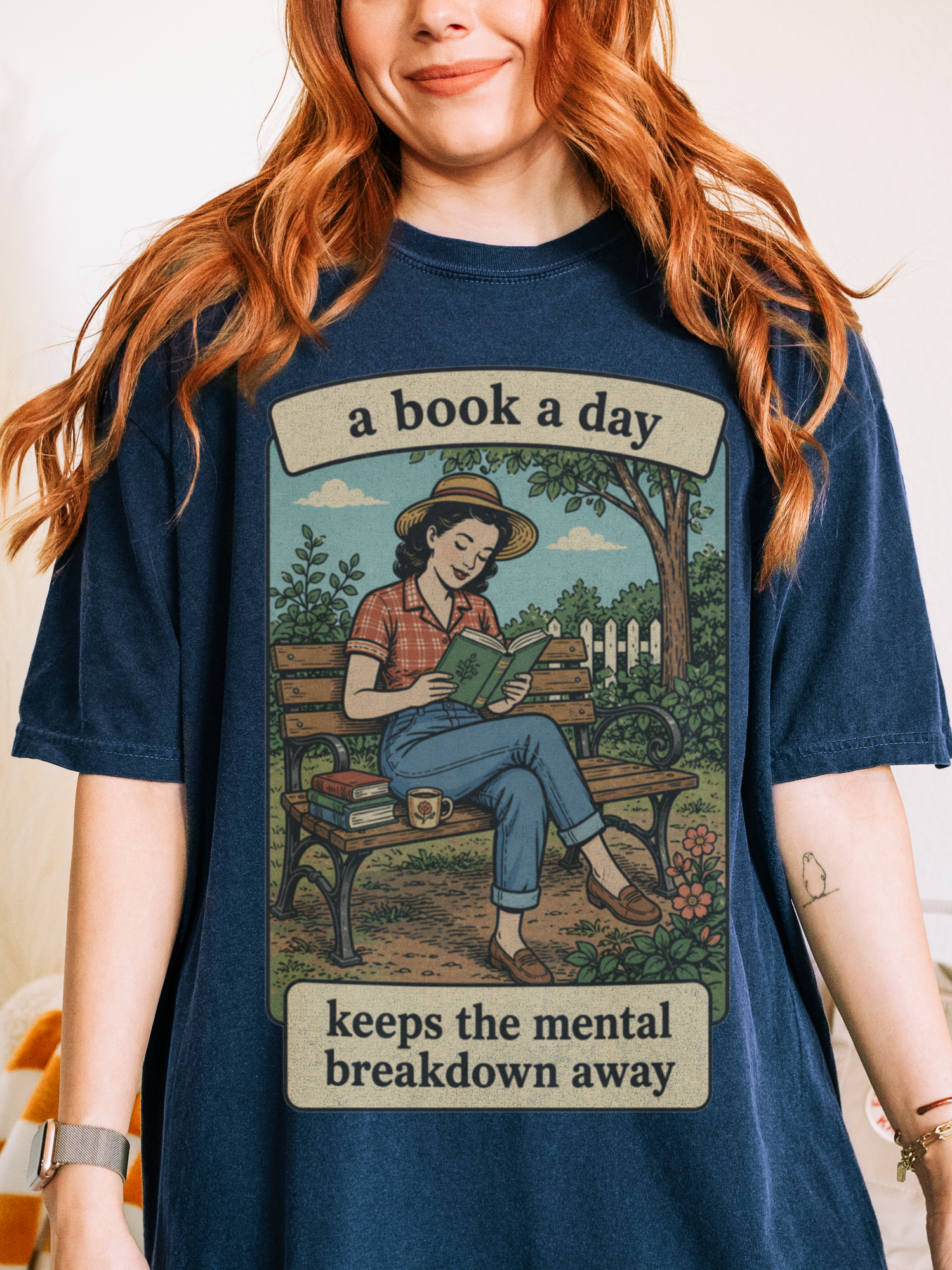 Woman wearing a true navy blue oversized t shirt with retro book lover graphic of woman reading on a park bench and text a book a day keeps the mental breakdown away