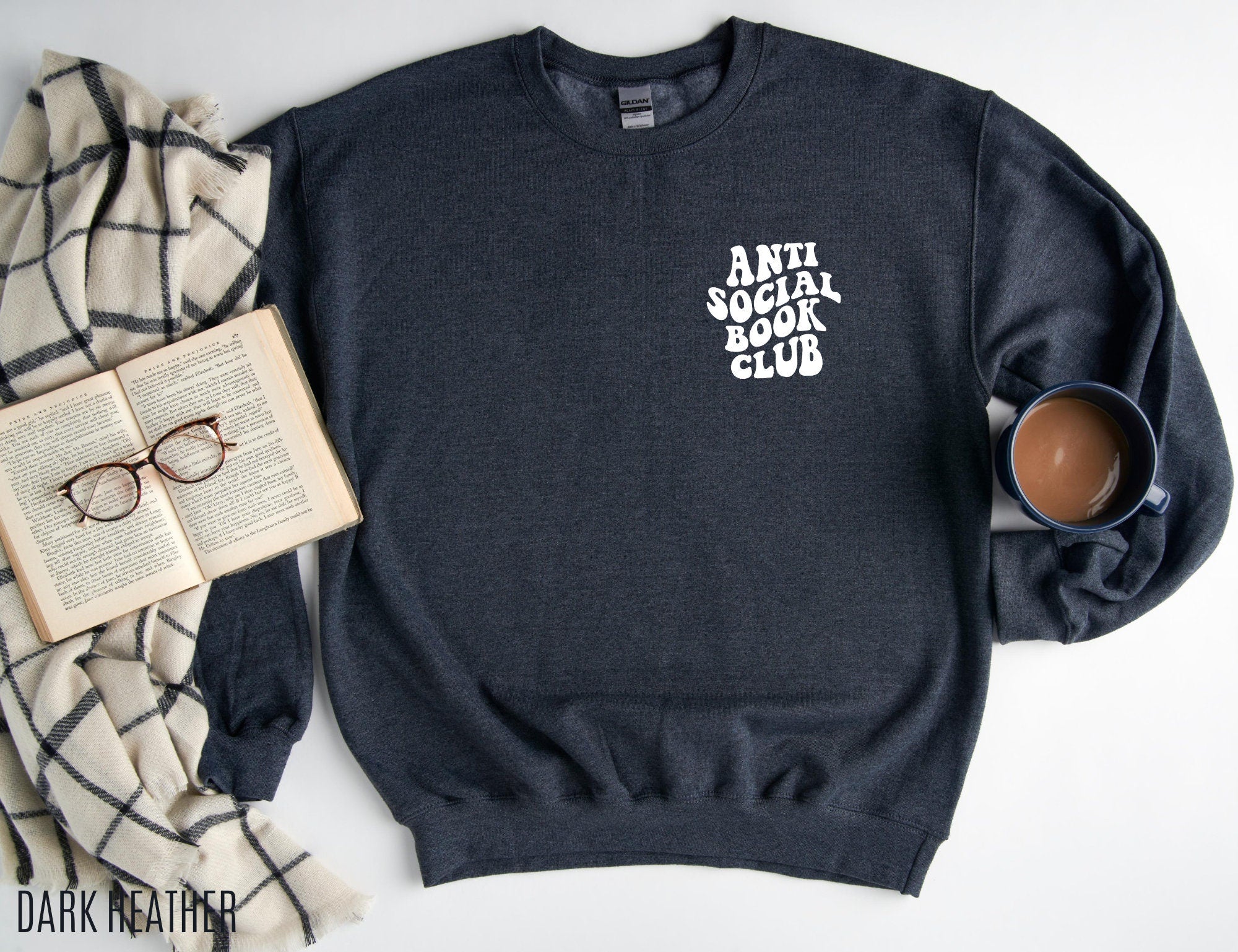 dark heather sweatshirt with anti social book club text laid flat with coffee, open book and plaid blanket