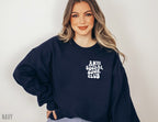 woman wearing navy sweatshirt that says anti social book club standing against neutral wall
