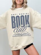 woman wearing oversized sand sweatshirt that says anti social book club with navy font design