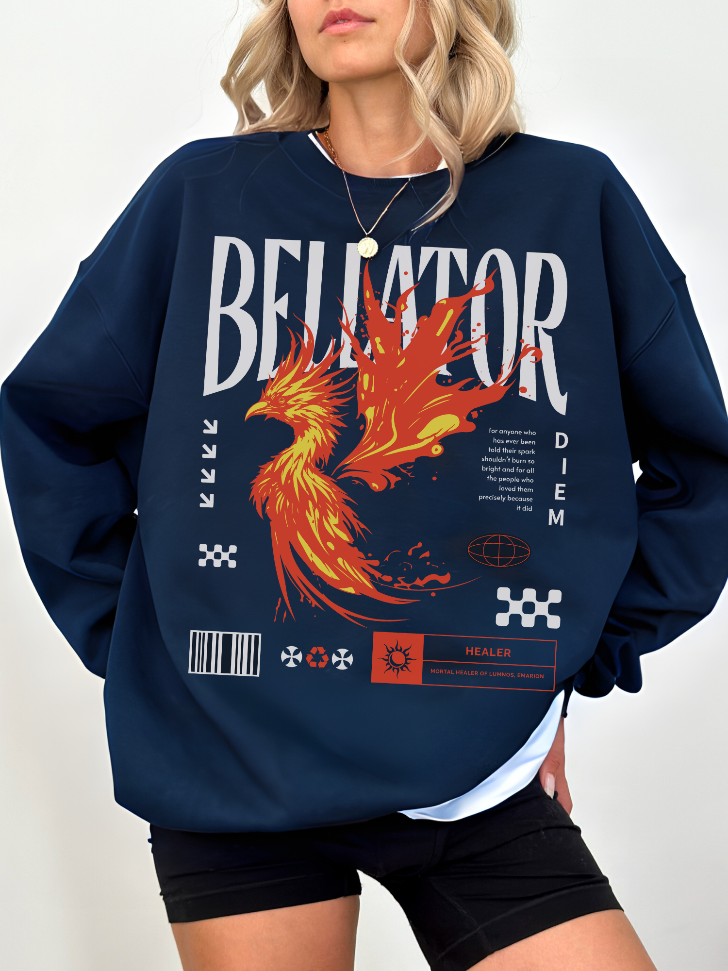 Navy crewneck sweatshirt with vivid red-orange phoenix flame and fantasy-inspired graphic. Model wearing layered white tee underneath, posing confidently.

